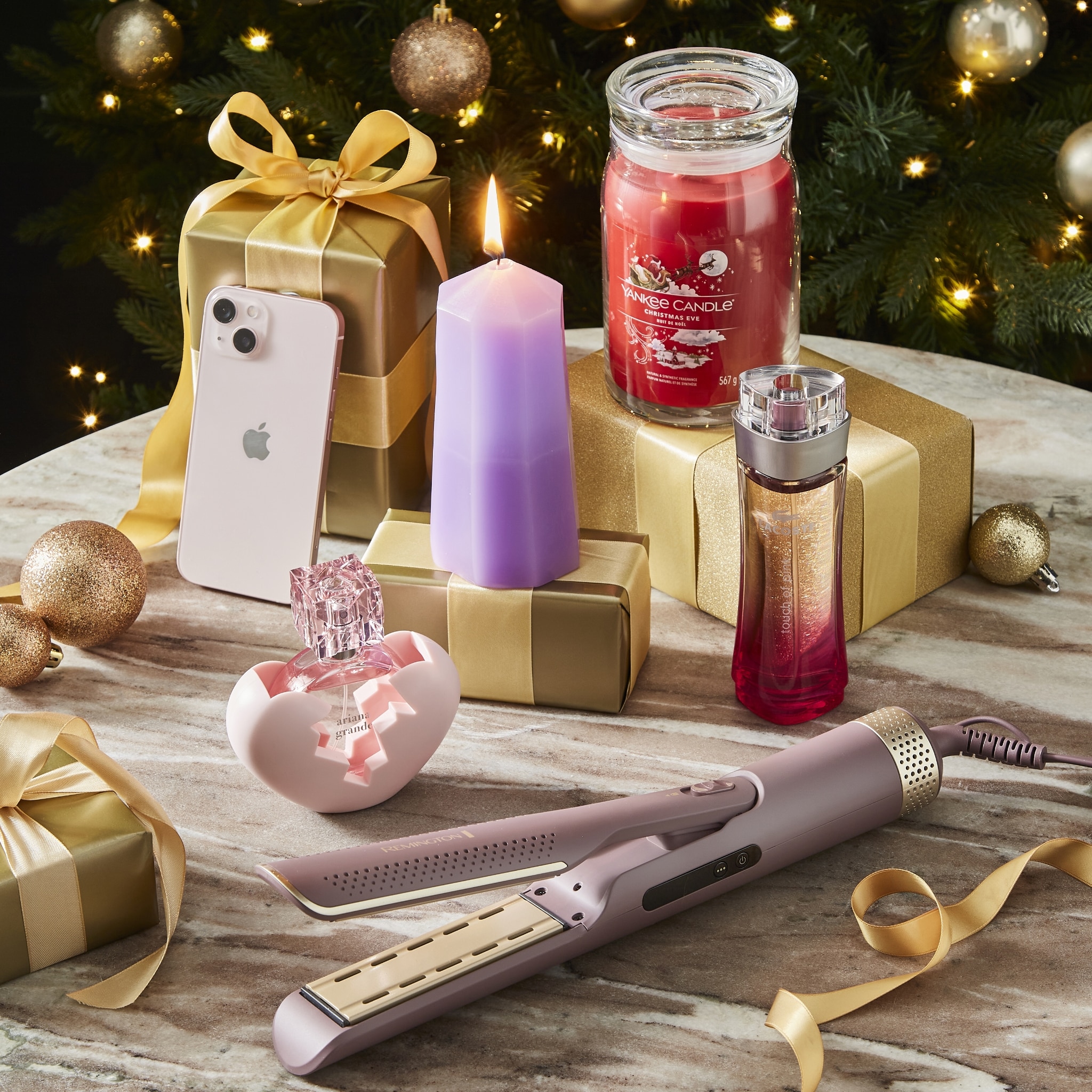 Christmas Gift Scene With Candles, Perfume, Present Boxes, and Hair Straightener on Table