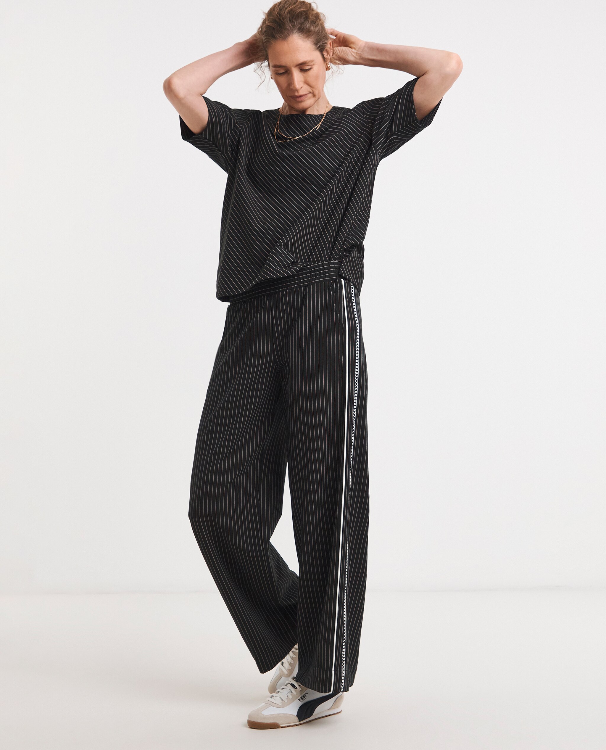 Model is wearing a striped structured sleeve co-ord top with trousers with a side panel.