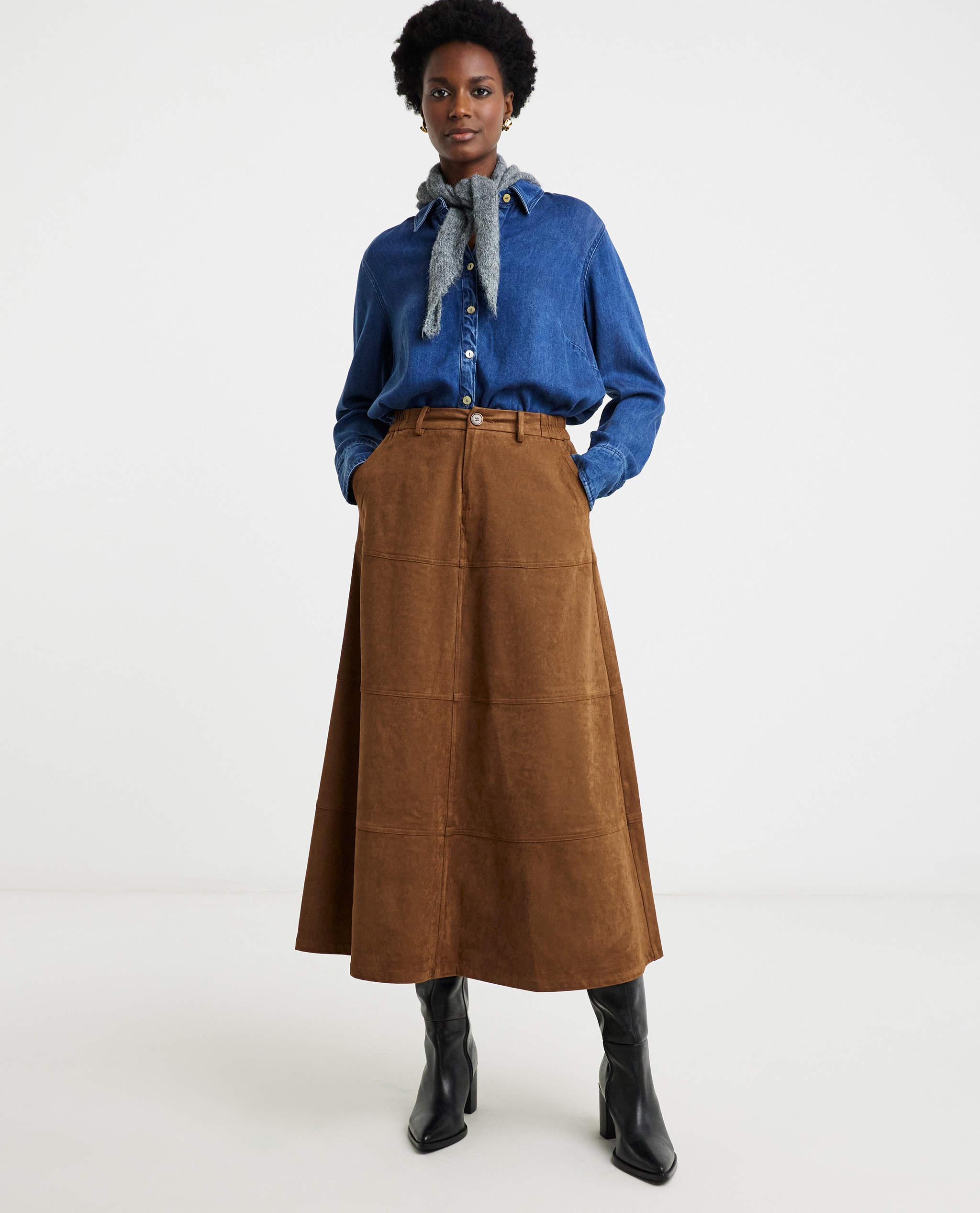 Model is wearing a mid blue denim shirt with a tan suedette skirt and a neck scarf and a pair of black boots.