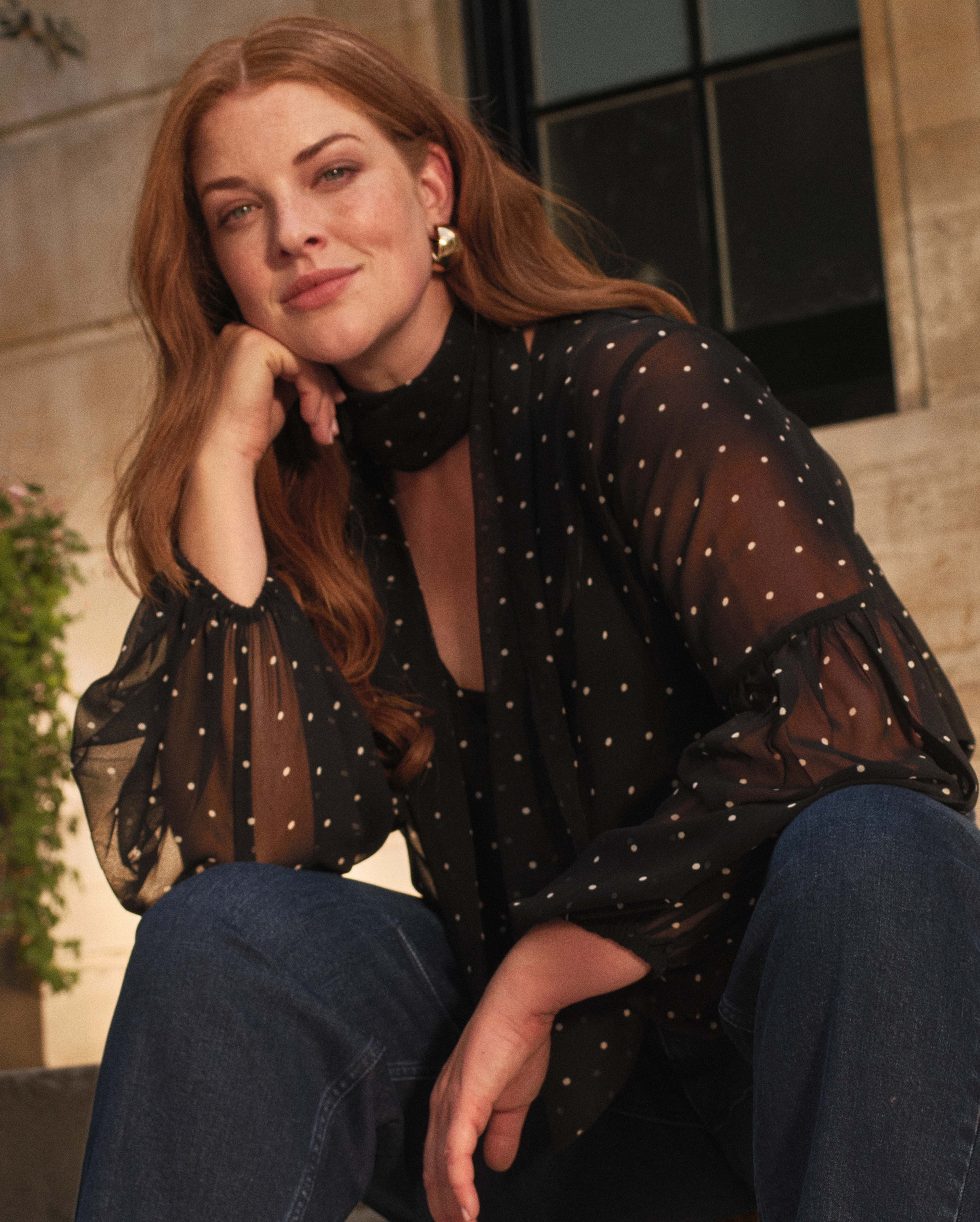 A lady wearing a black top with white spots on it.