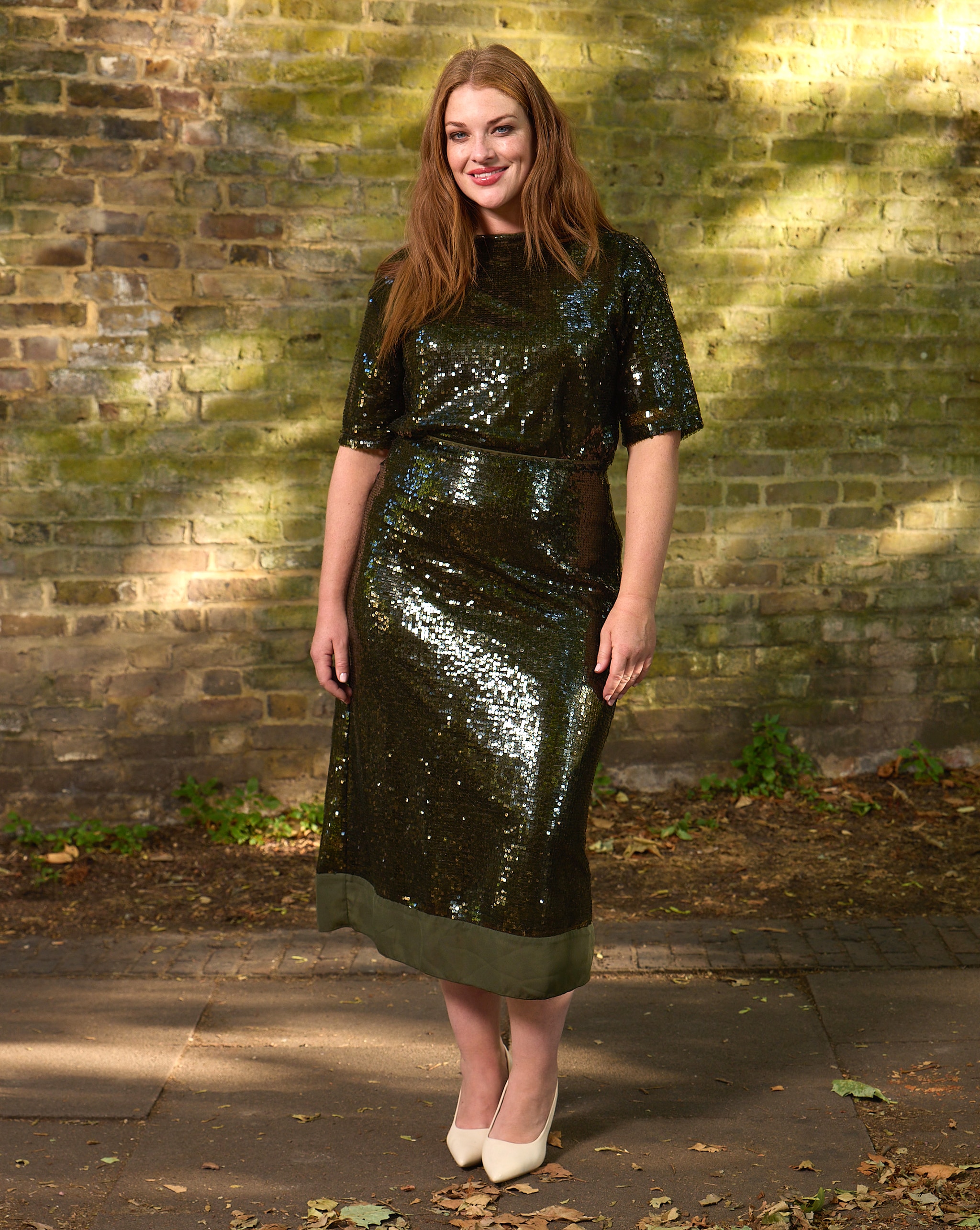 A lady stood outside wearing a green sparkly dress