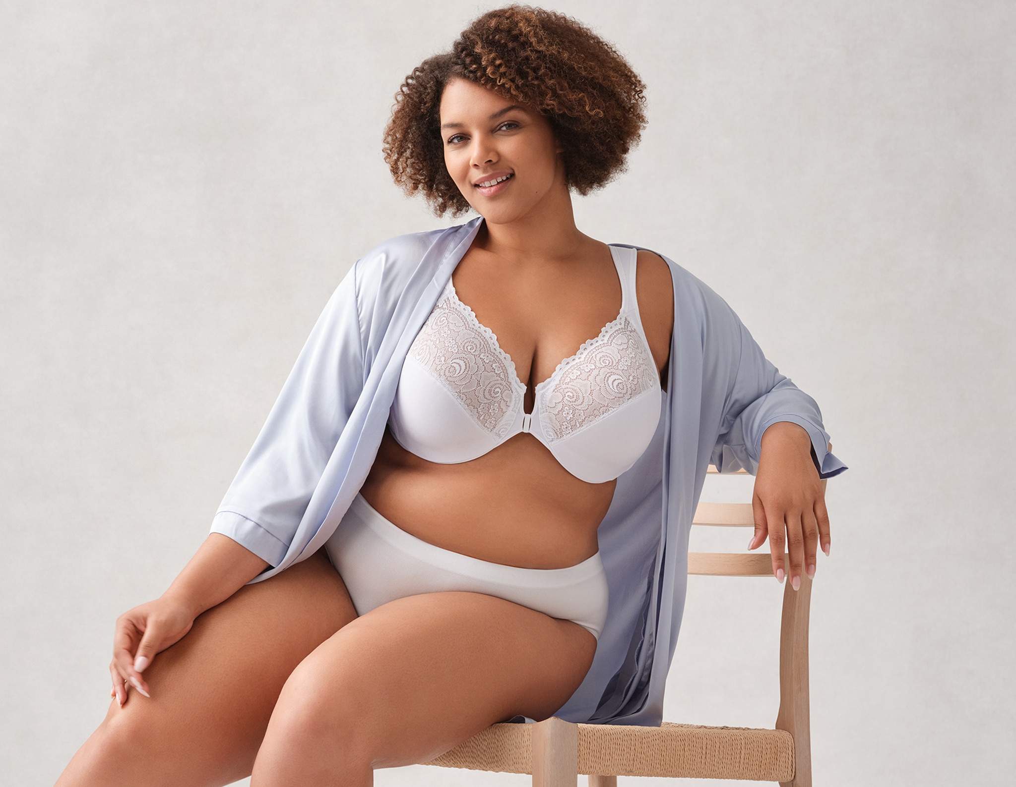 A woman sat on a chair wearing white bra and knickers