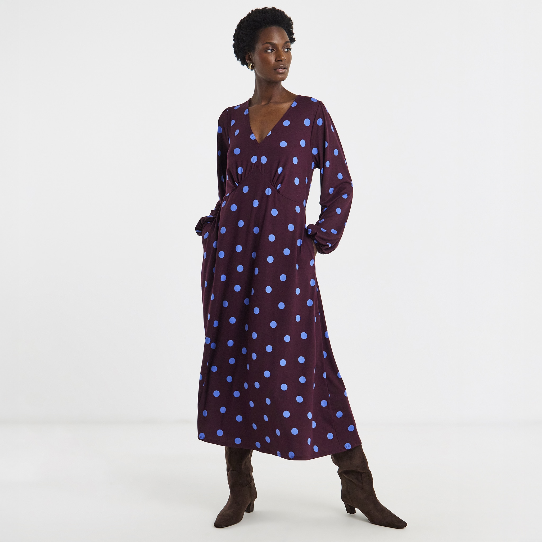 A lady wearing a purple dress with pale blue spots on it,