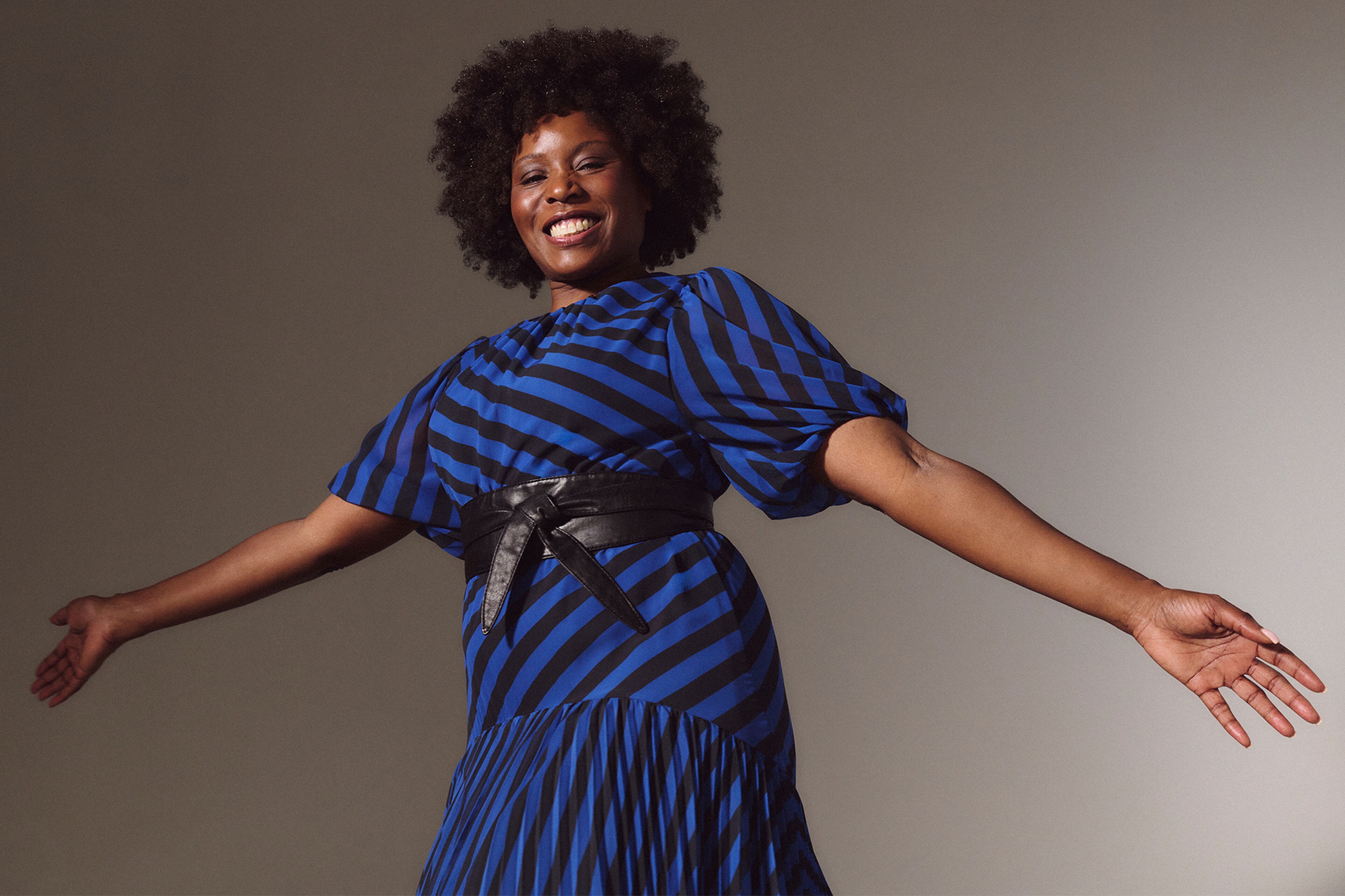 A lady stood with her arms out wide wearing a Joanna Hope stripe print tea dress
