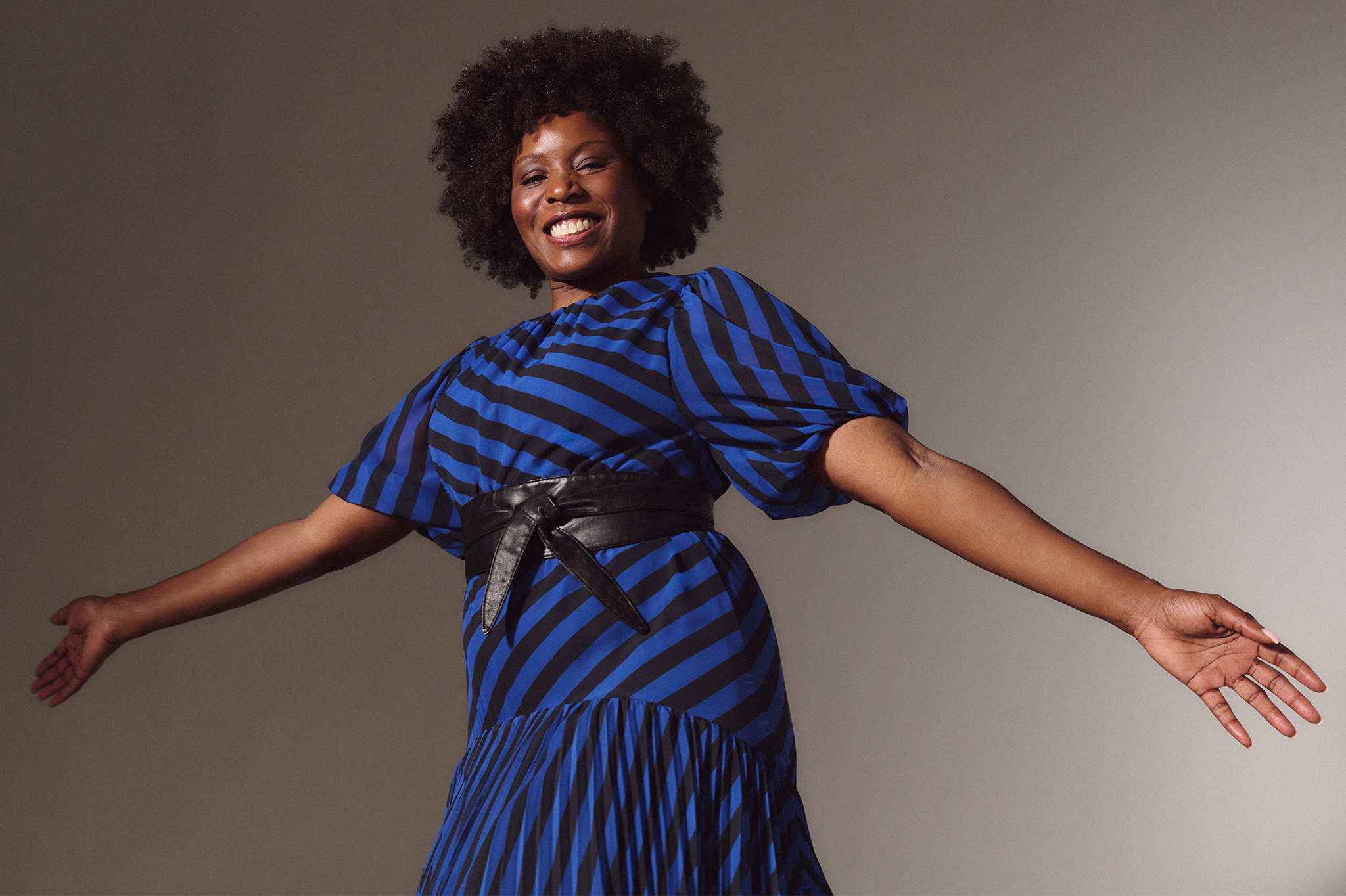 A lady stood with her arms out wide wearing a Joanna Hope stripe print tea dress