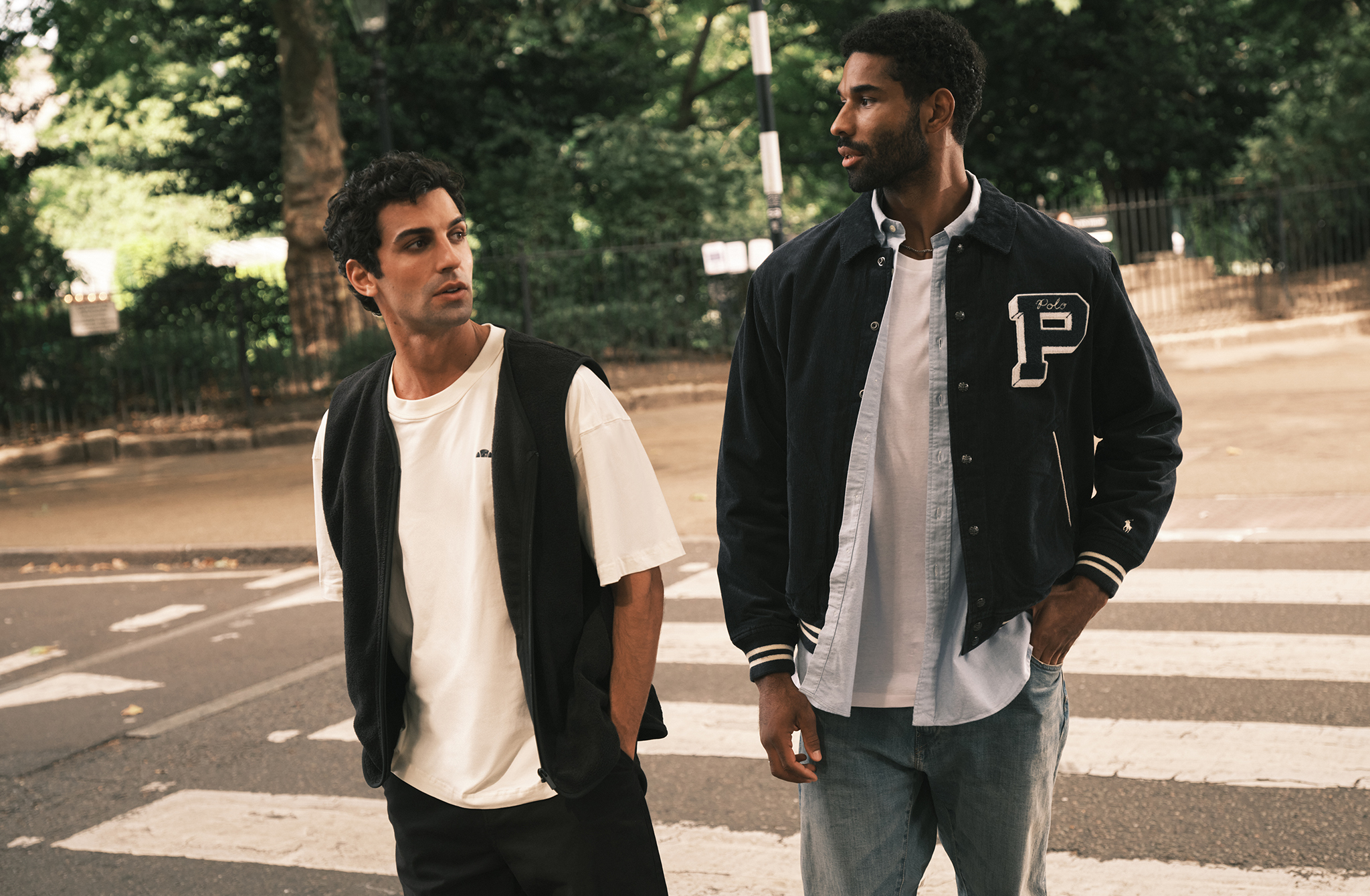 Two people walking and talking as they walk across a zebra crossing.