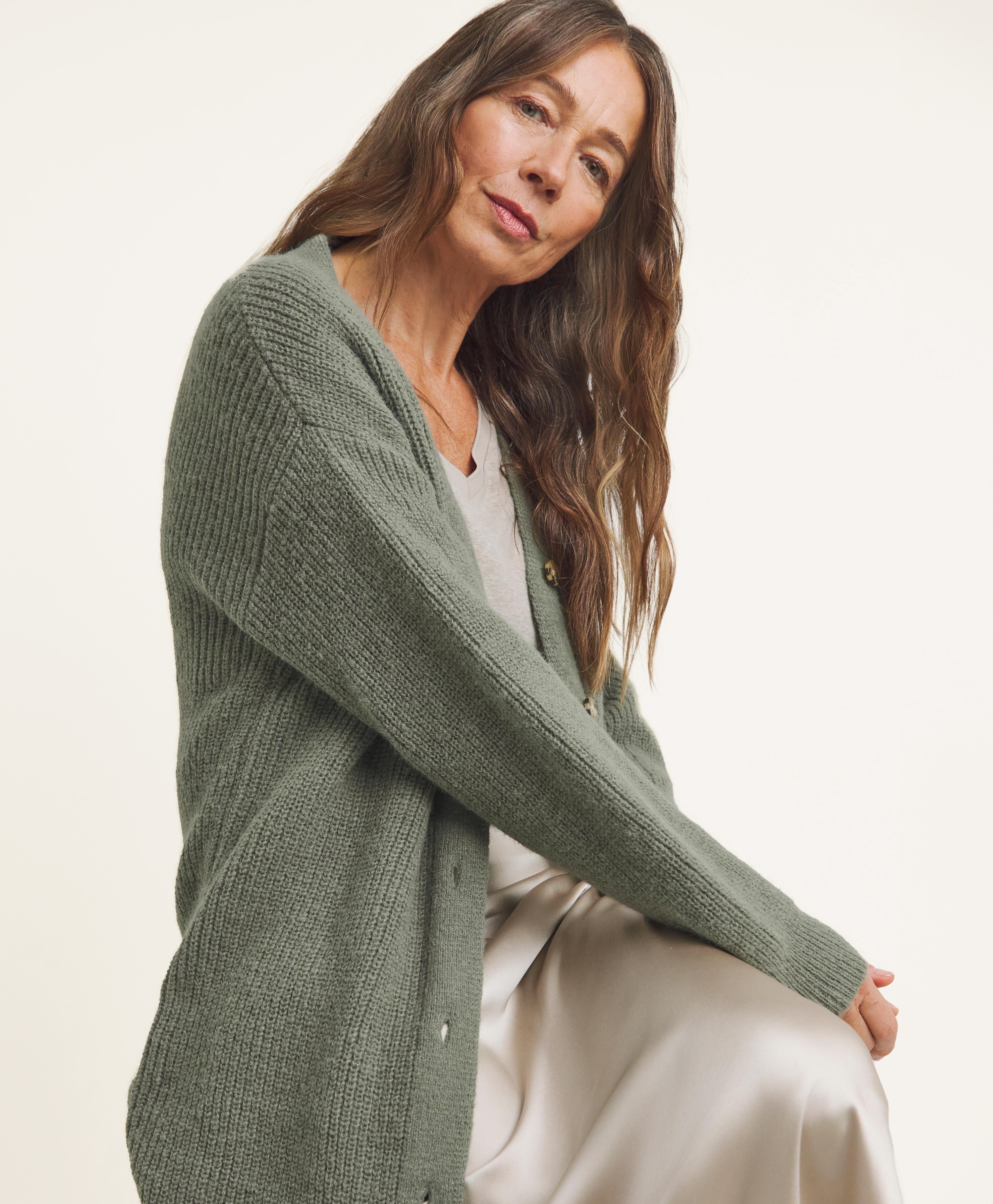 Lady sat sideways wearing green button up cardigan