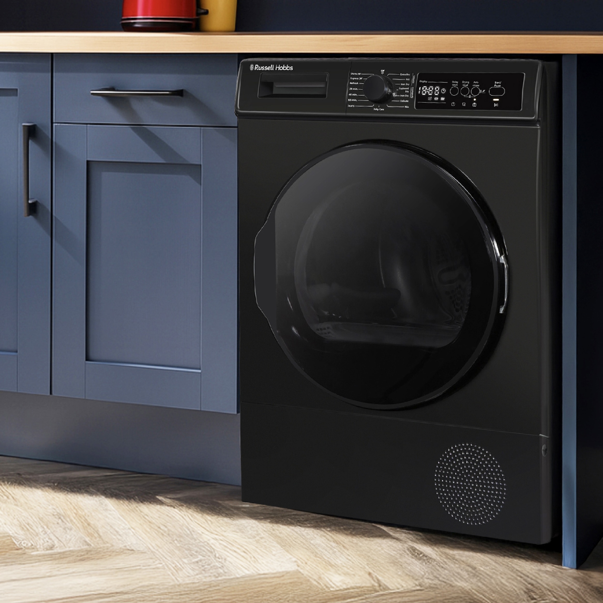 Black russell hobbs tumble dryer installed under blue kitchen cabinets.