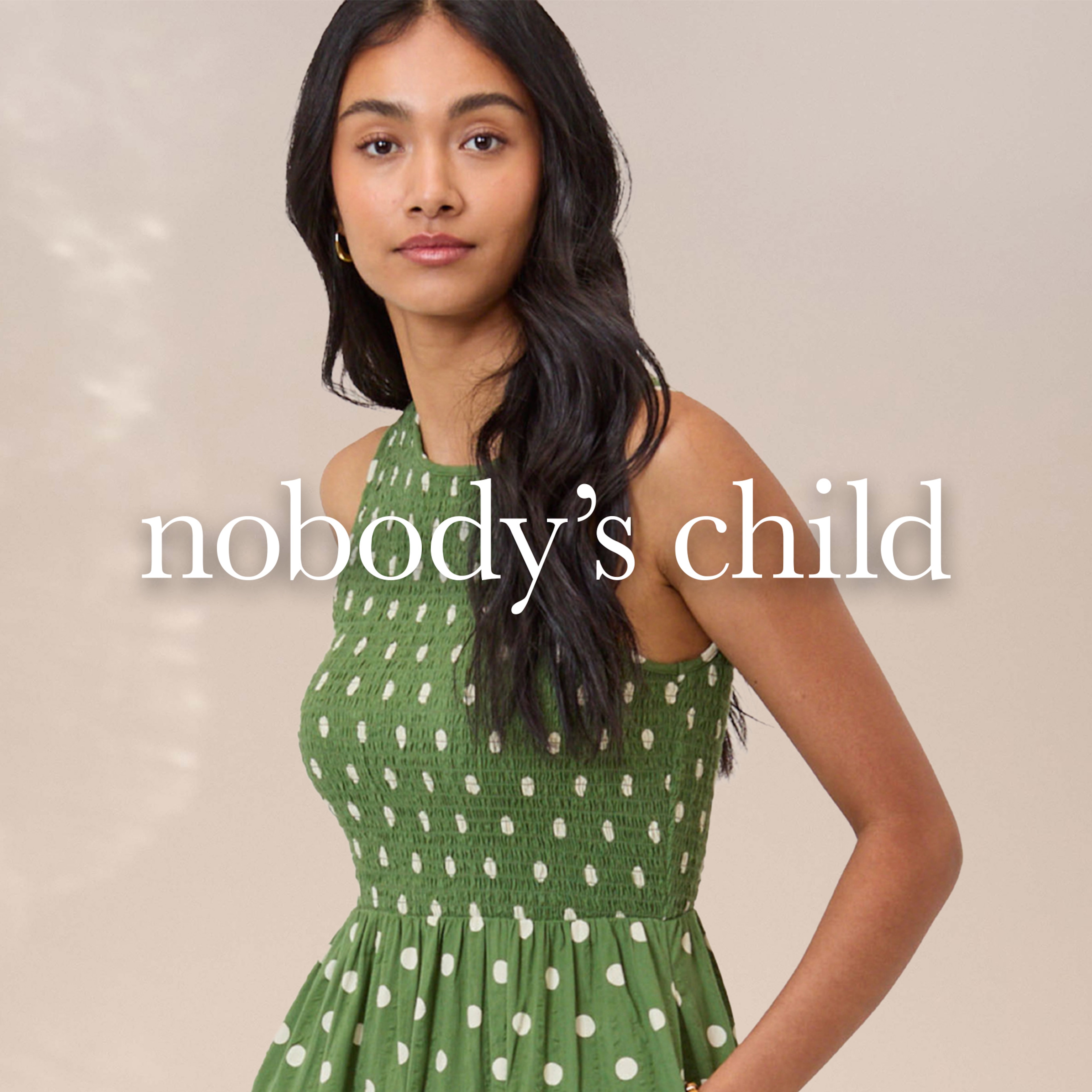 A lady wearing a green sleeveless Nobody's Child dress.