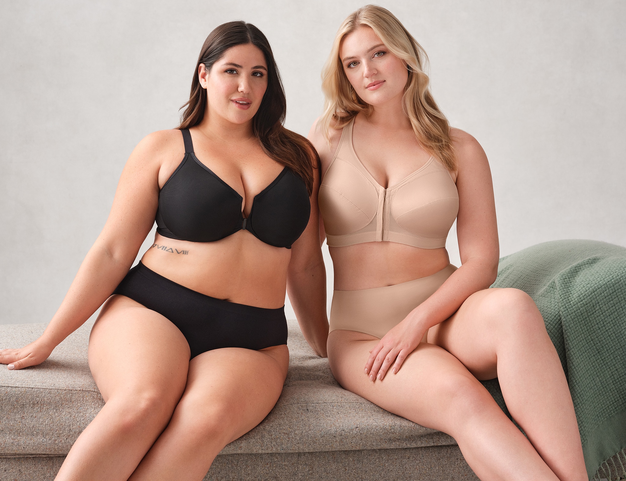 Two women wearing black and nude underwear respectively