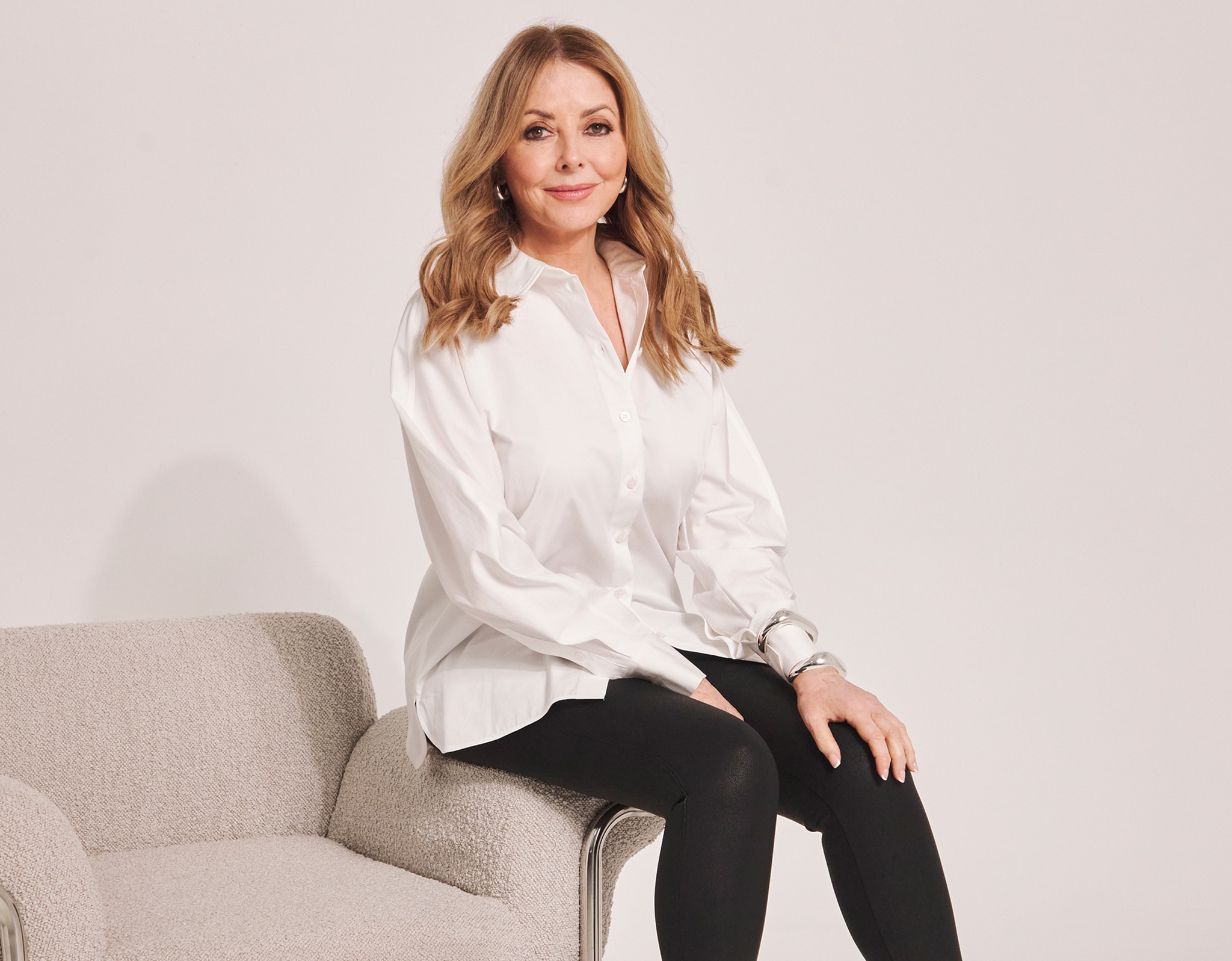Carol Vorderman sat down with her hands on her knees wearing a white blouse and black trousers.