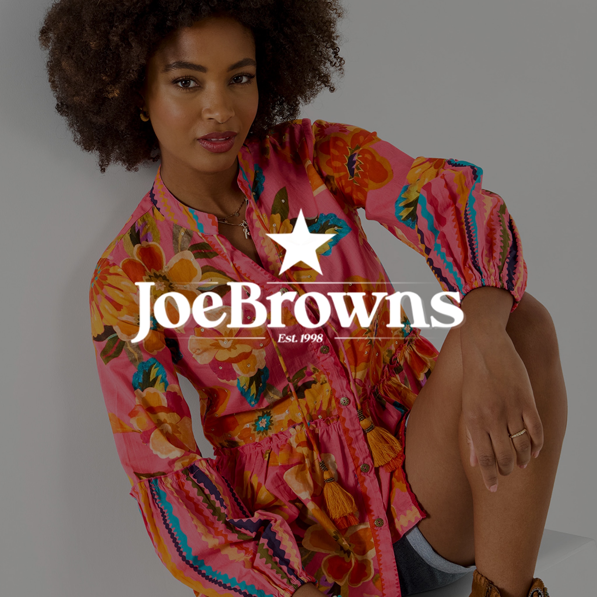 A lady wearing a Joe Browns dress. The Joe Browns logo is over laid on top of the image