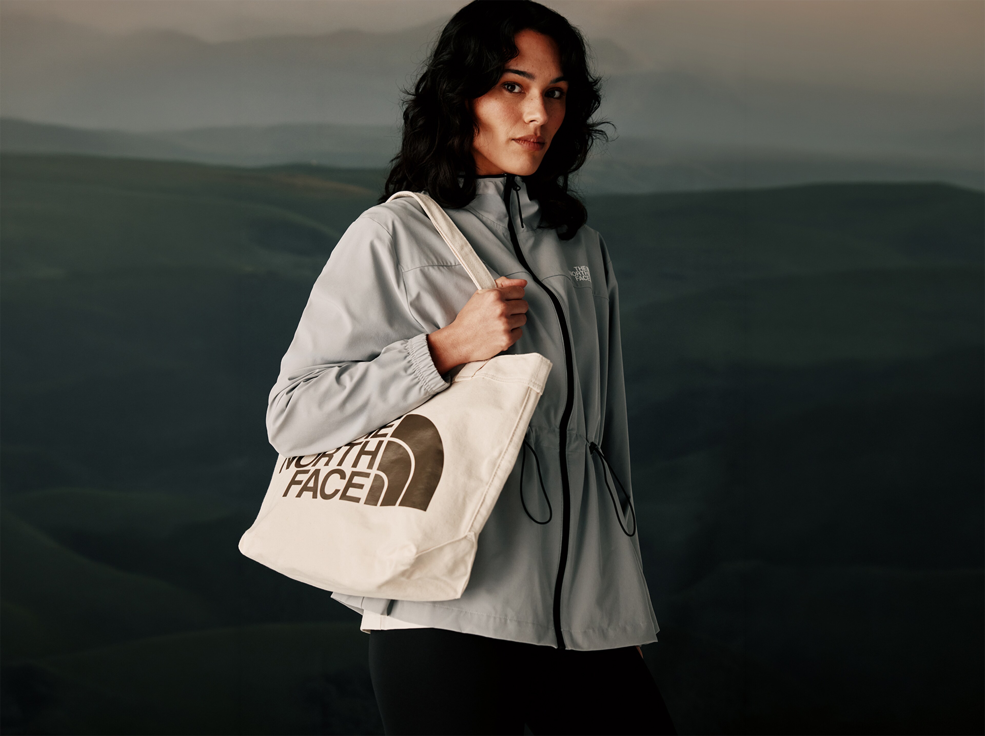 A lady wearing a North Face coat and holder a bag on her right shoulder. 