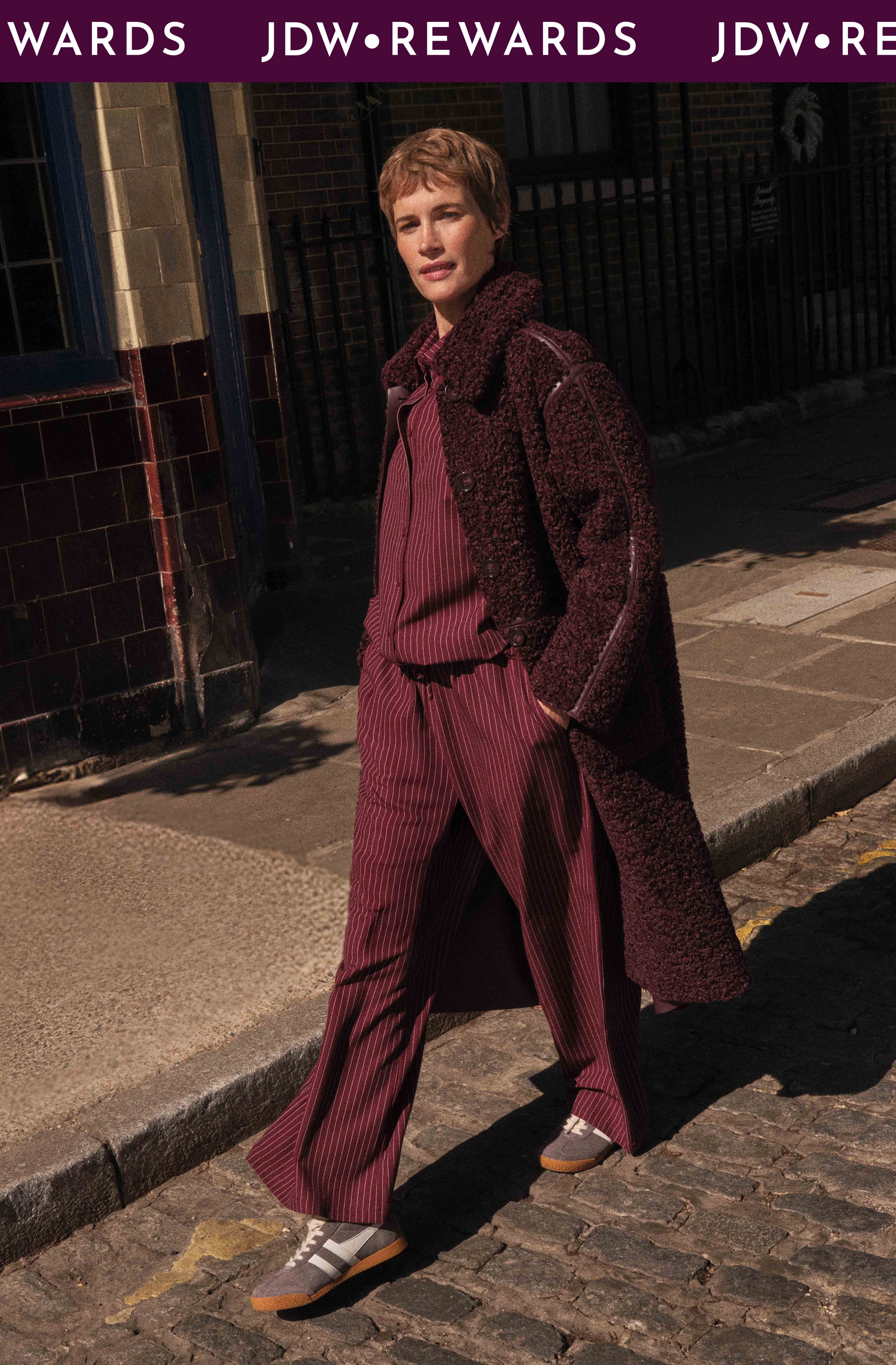 A lady walking on a sunny day wearing maroon clothing