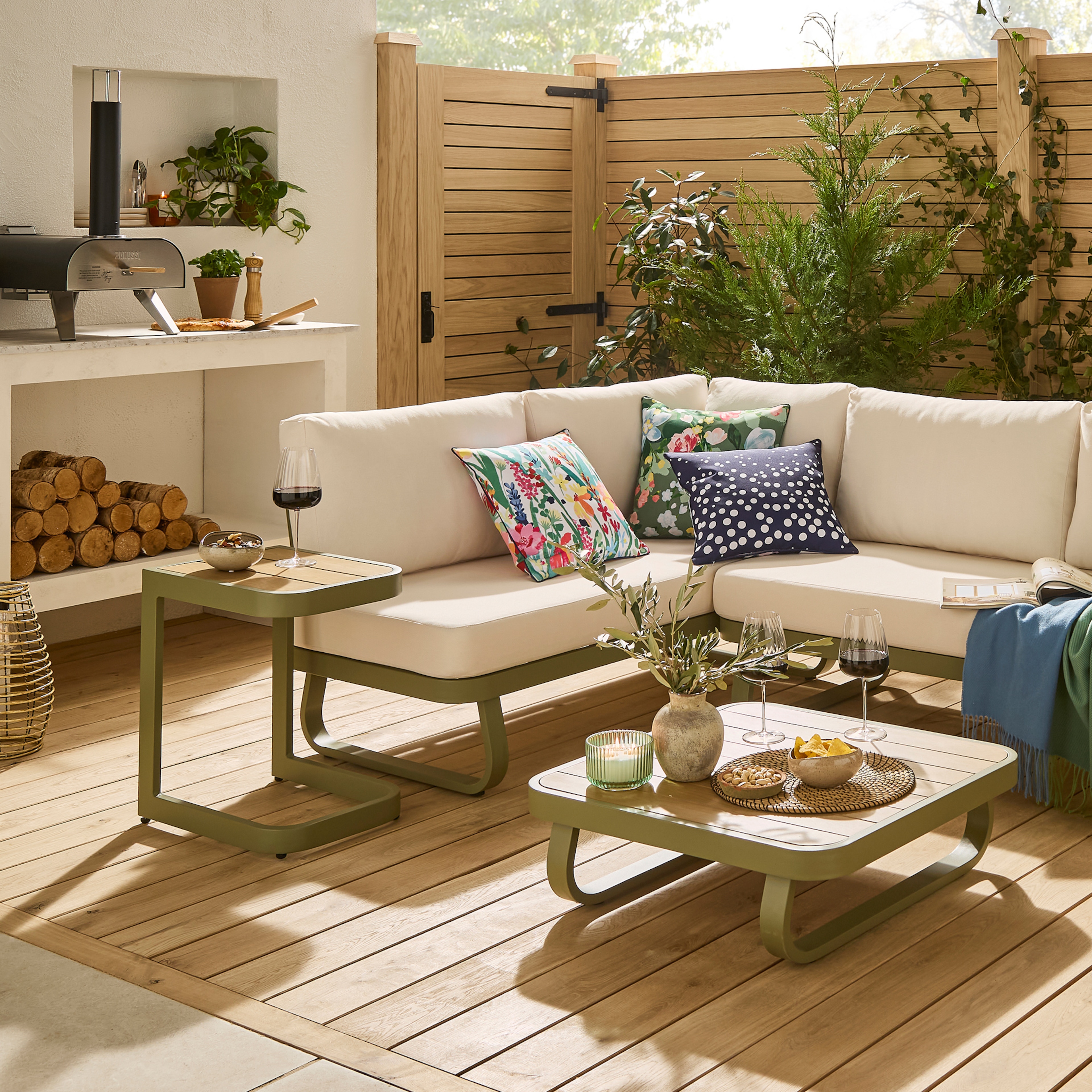 A garden scene with an L shaped corner sofa with a table with drinks and nibbles on it.