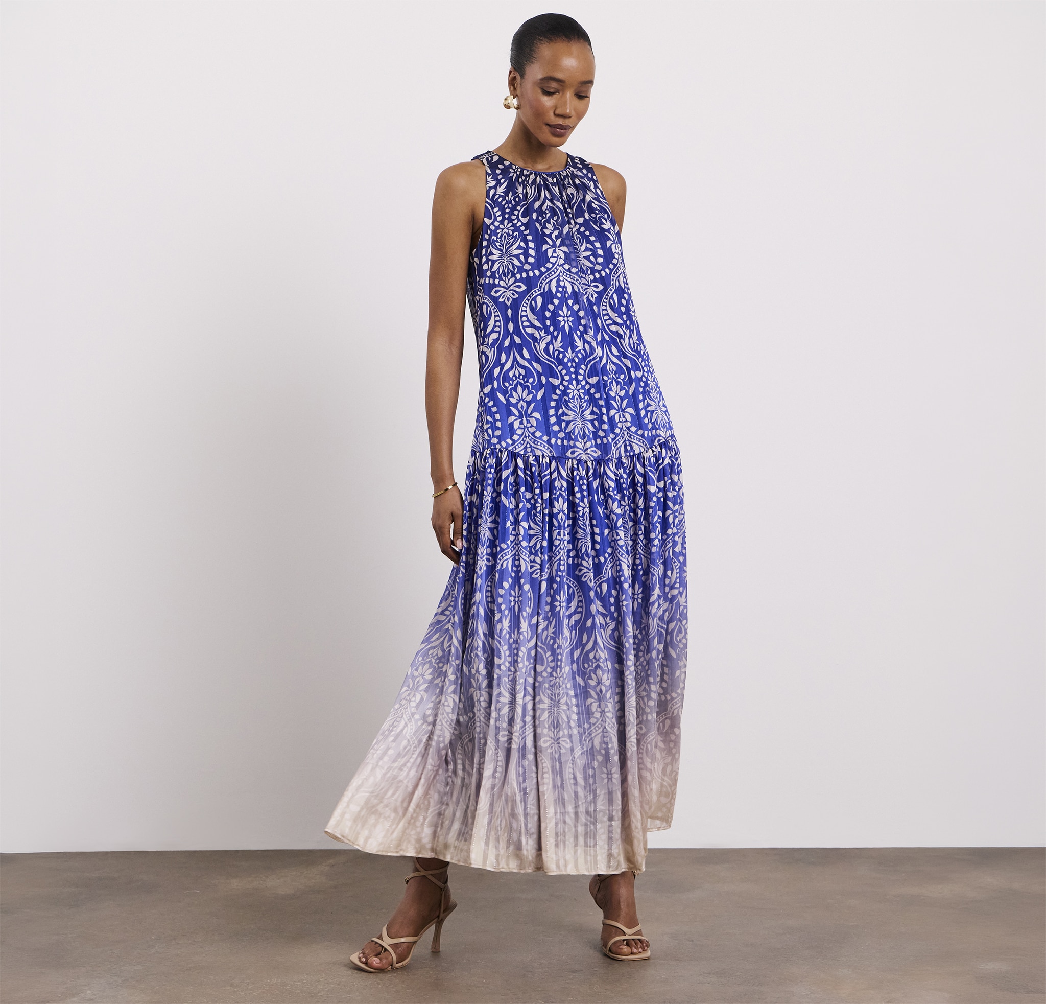 A lady stood wearing a Joanna Hope printed halter neck dress with metallic thread