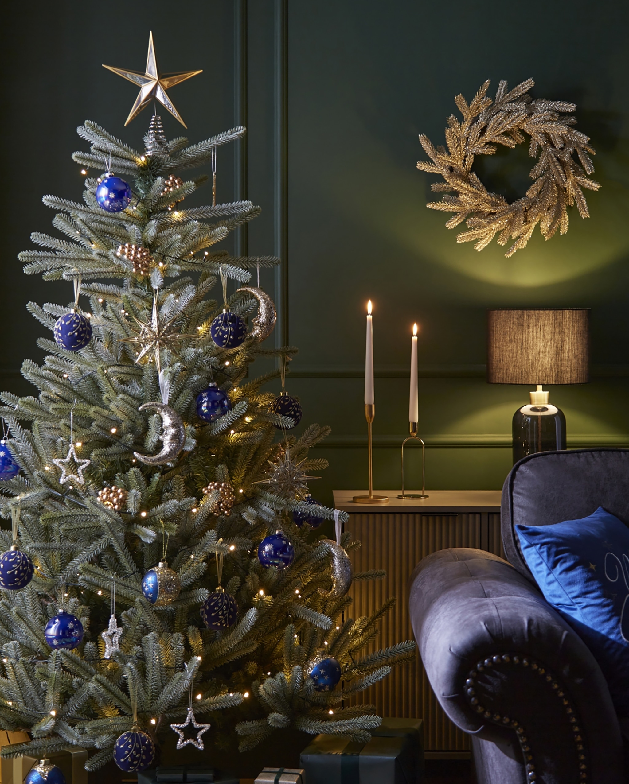 Cozy Christmas Living Room With Frosted Tree, Blue Ornaments, Golden Wreath And Warm Lighting