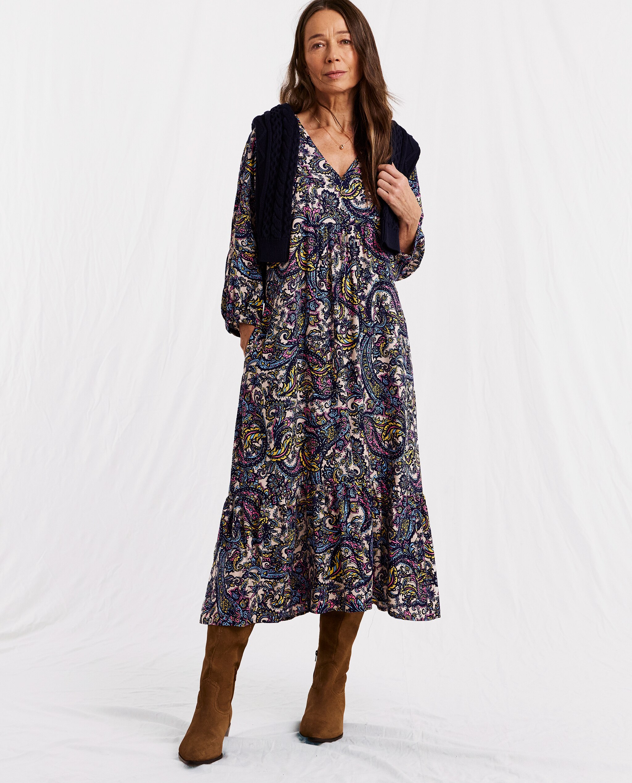 Model is wearing a printed tiered midi dress with tan boots.