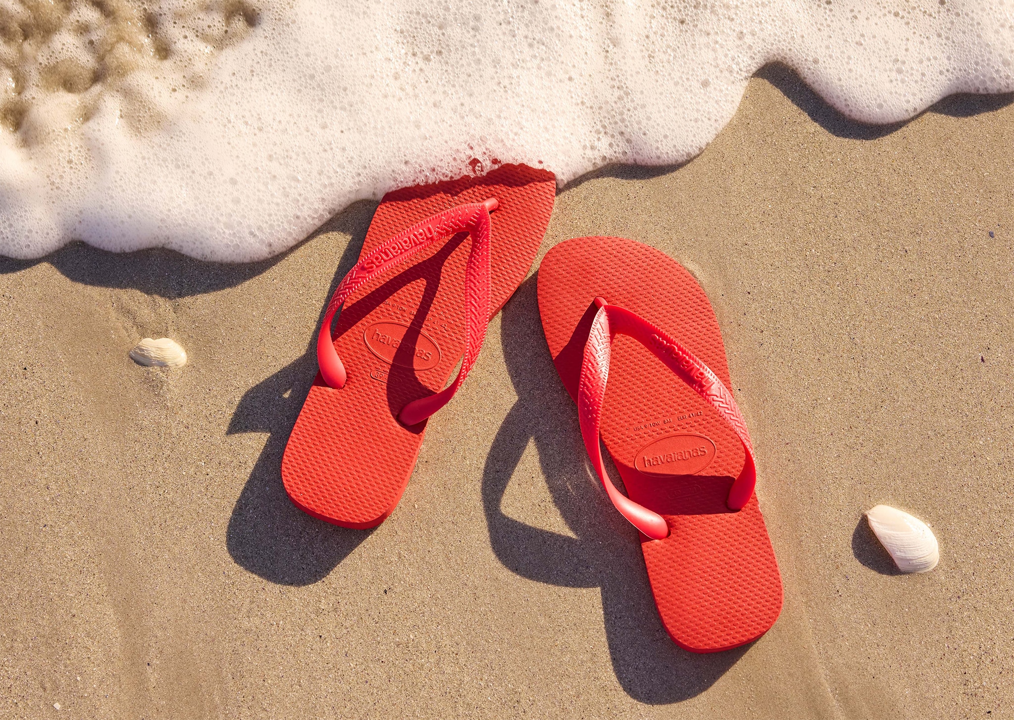 Red sandals on the sand about to be covered with the sea
