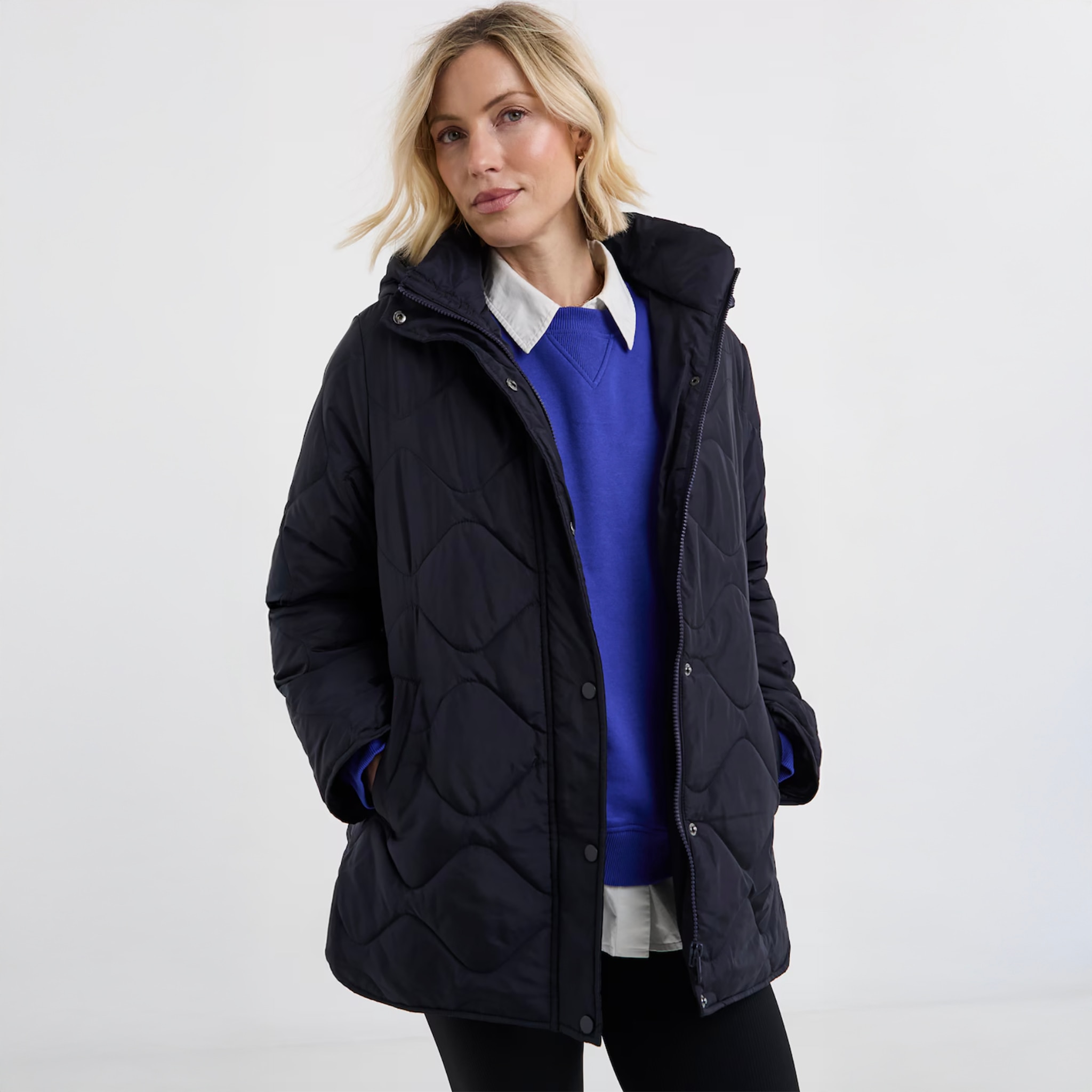 A lady wearing a royal blue jumper with a navy blue quilted coat on top.
