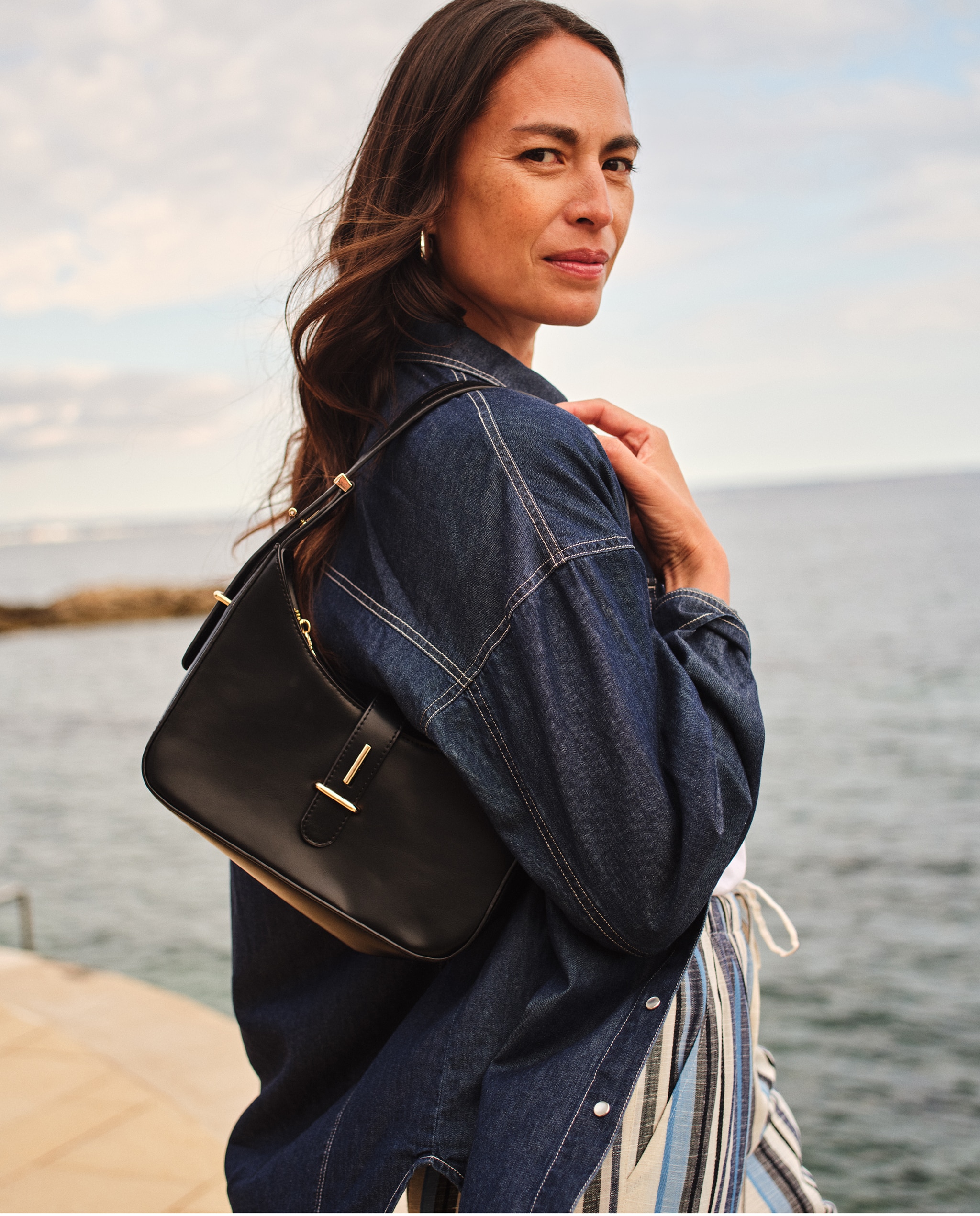 Lady wearing a denim jacket looking over her right shoulder.
