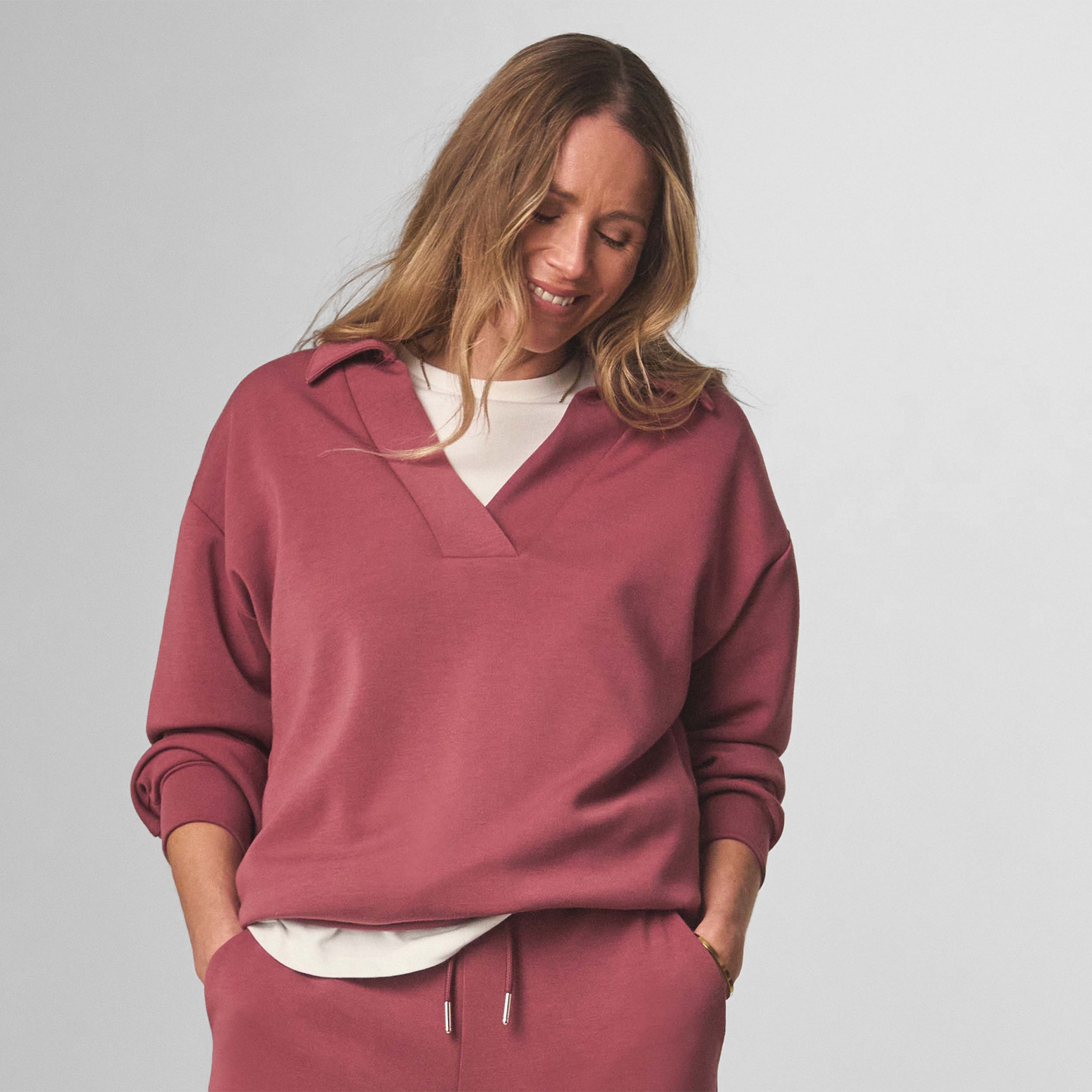 Lady wearing a red v-neck sweatshirt with matching trousers.