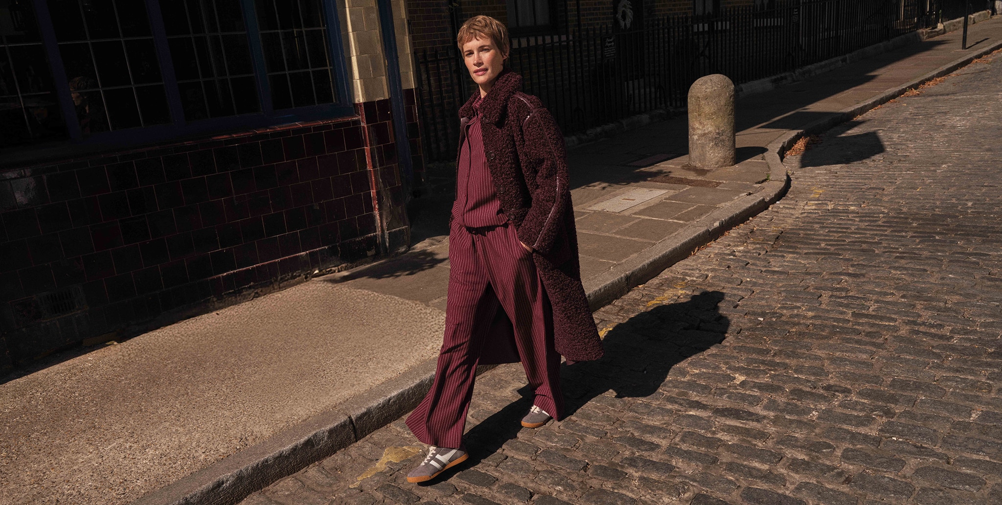 A lady wearing burgundy clothes wtih a similar colour long coat.