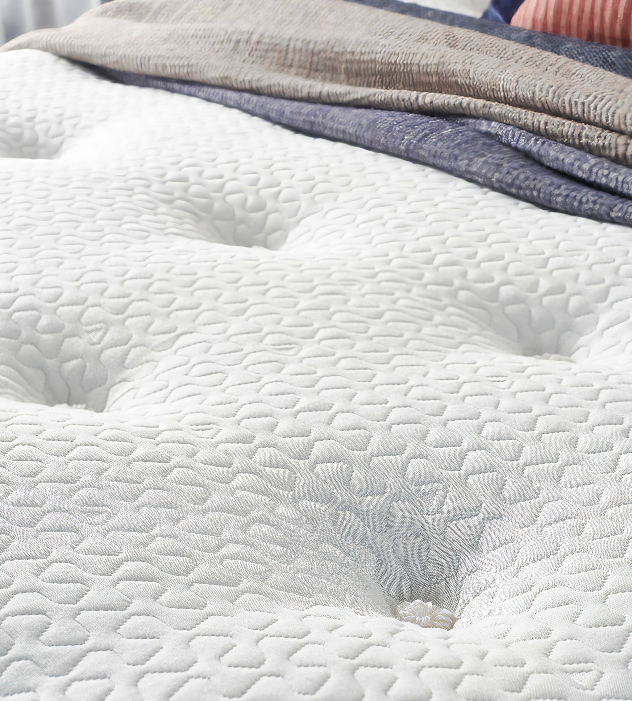 A bare mattress with layers of sheets folded at the top of the image