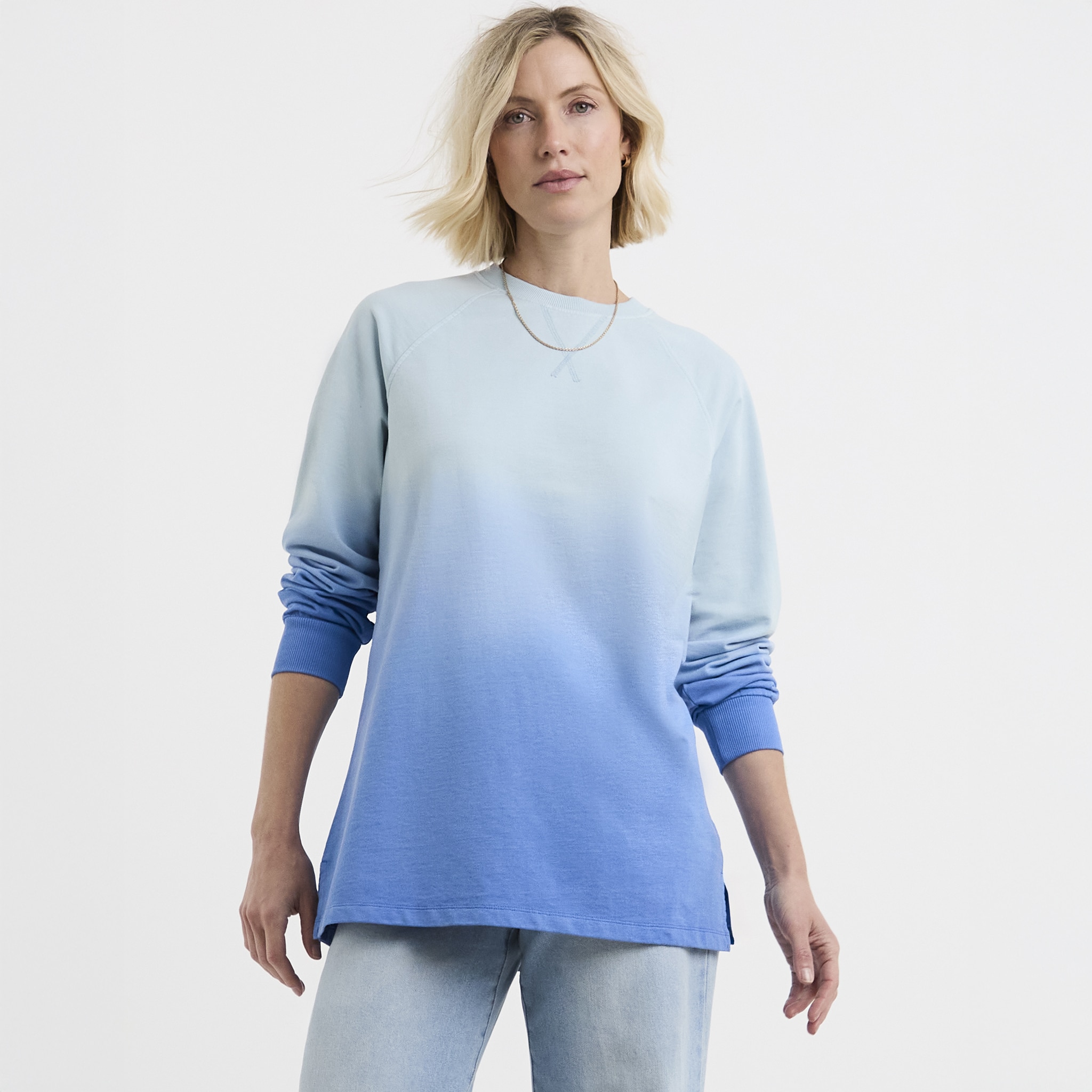 A lady wearing a longline sweatshirt in a blue ombre colour.