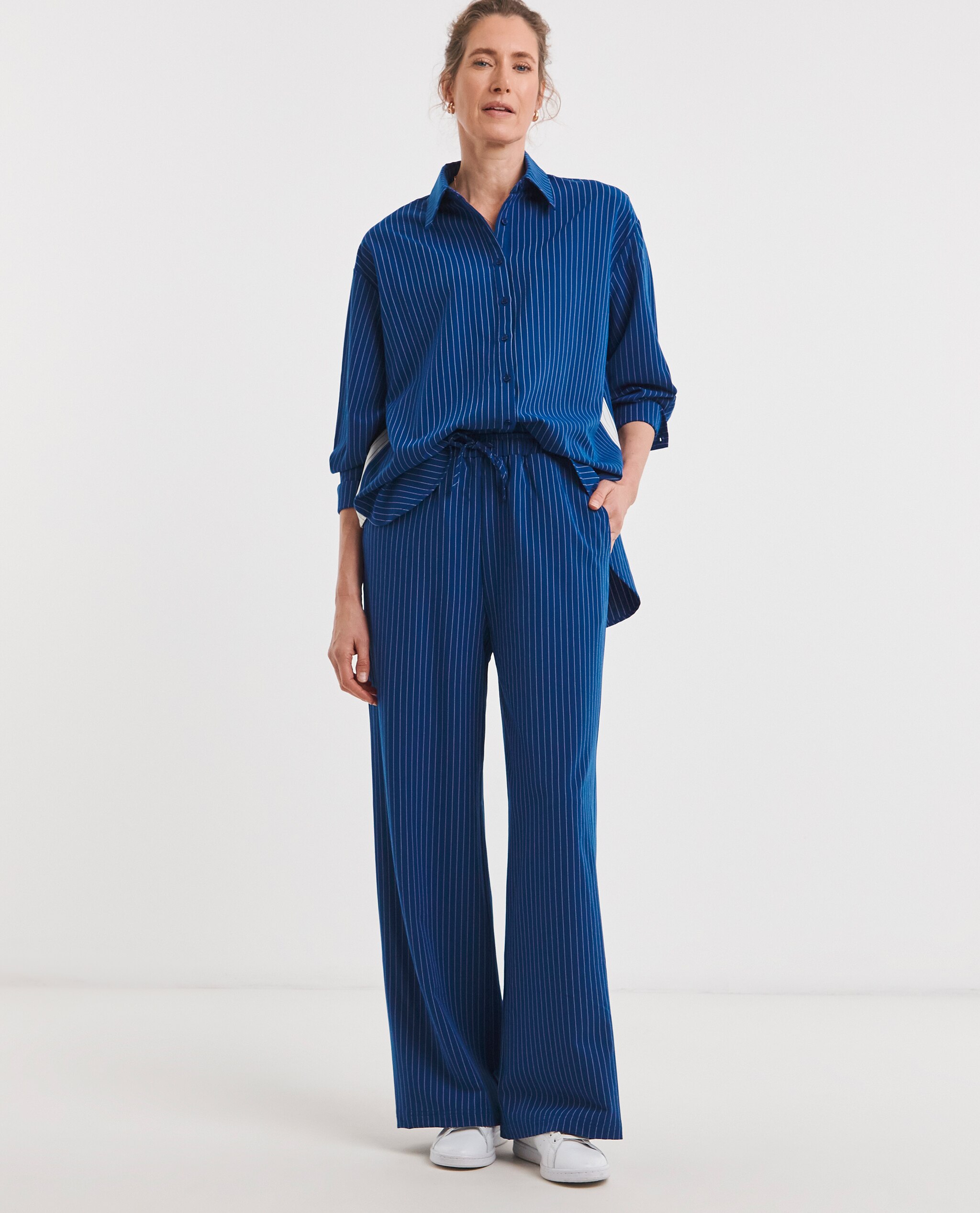 Model is wearing a stripe twill oversized long sleeve shirt with stripe drawstring wide leg trousers.