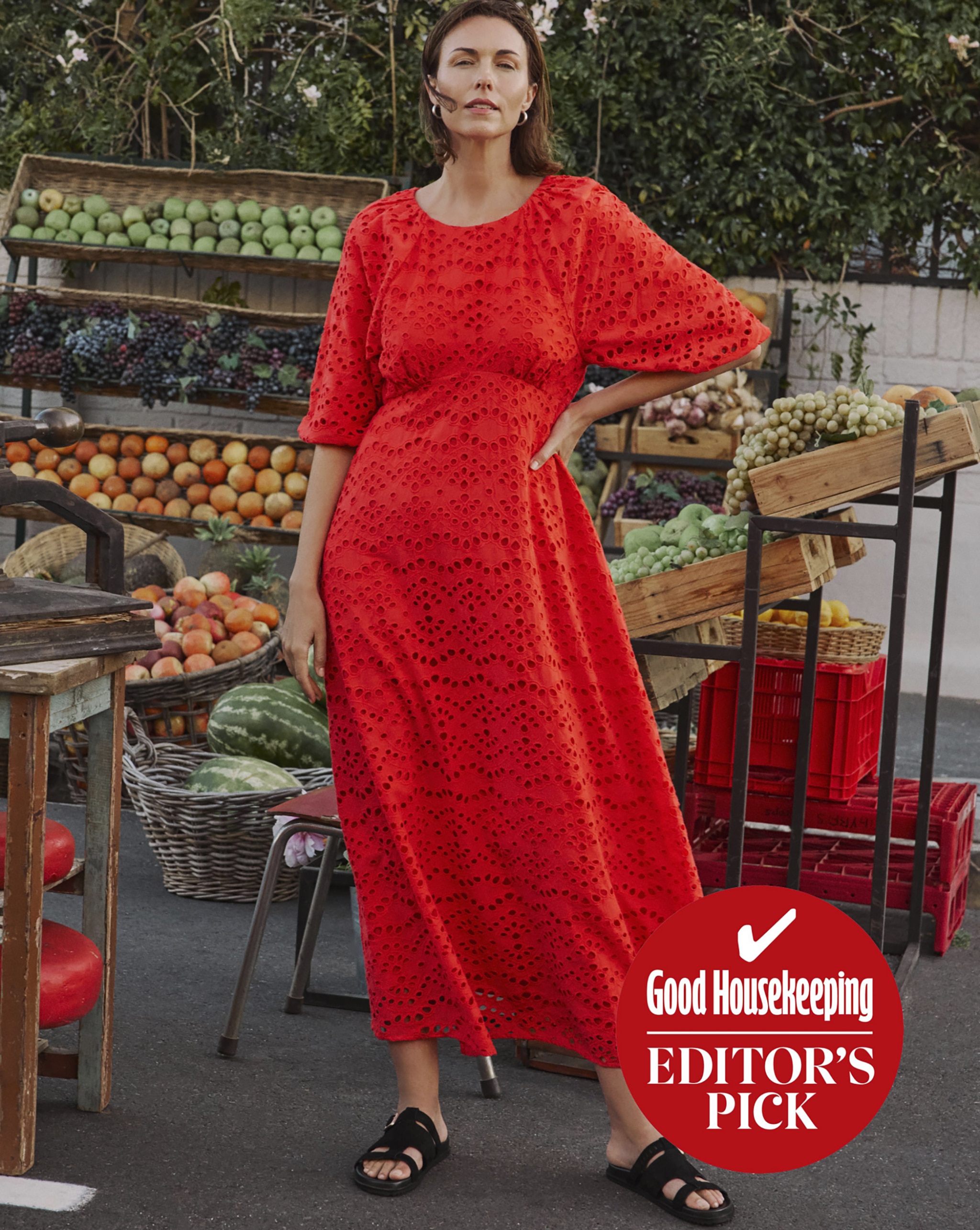 A lady wearing a red dress in front of a fruit stall