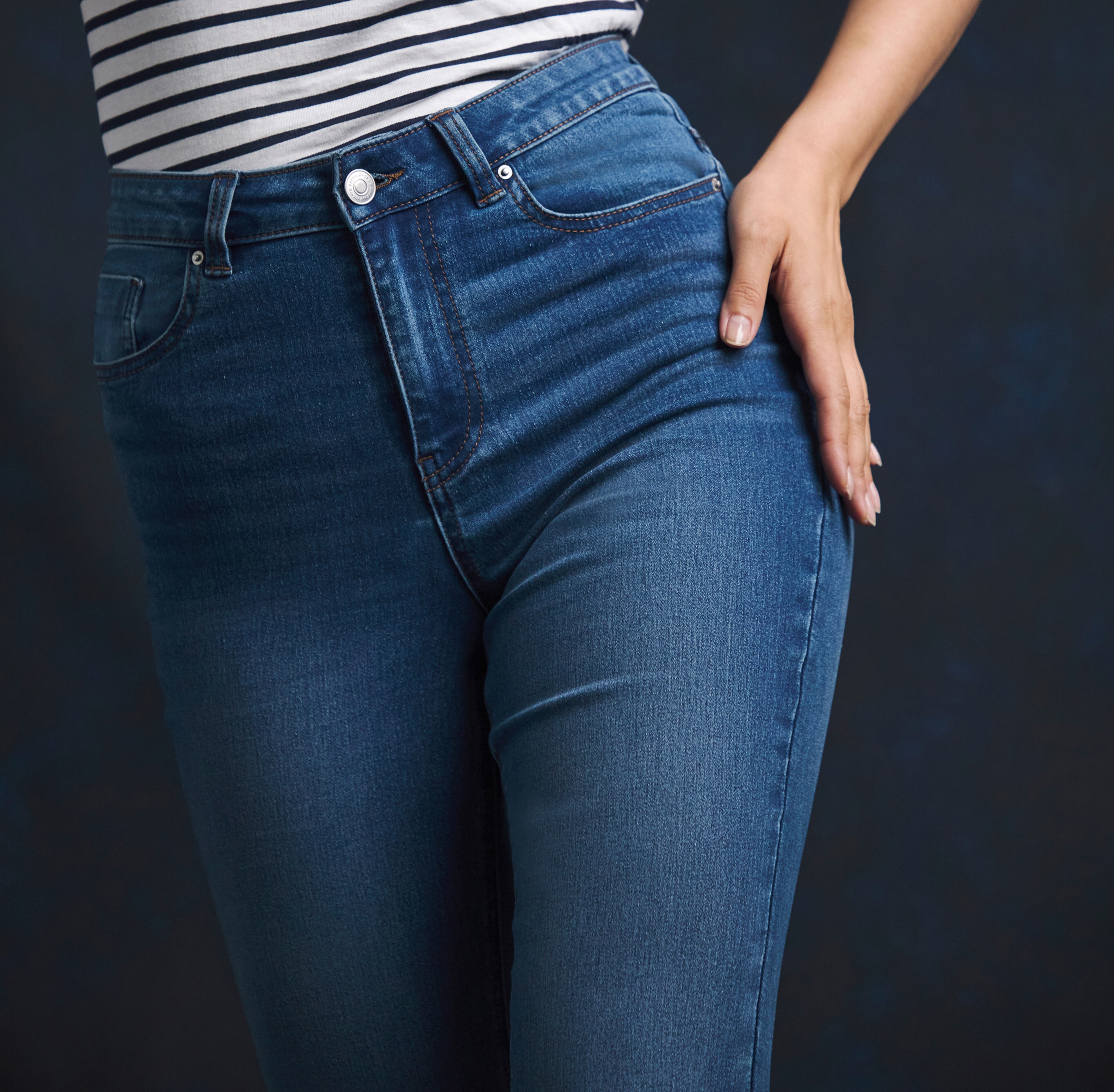Lady wearing blue jeans with hand on hip