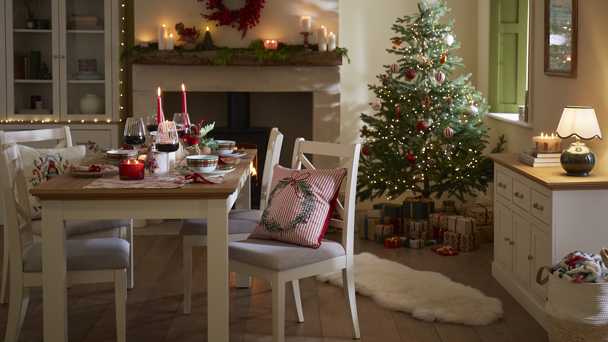 A Christmas themed dining room with a tree in the corner of the room.