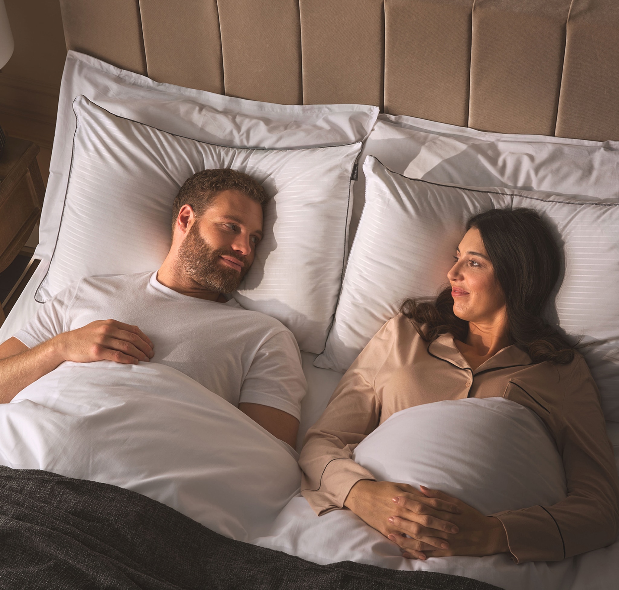 Two people looking at each other in a bed.