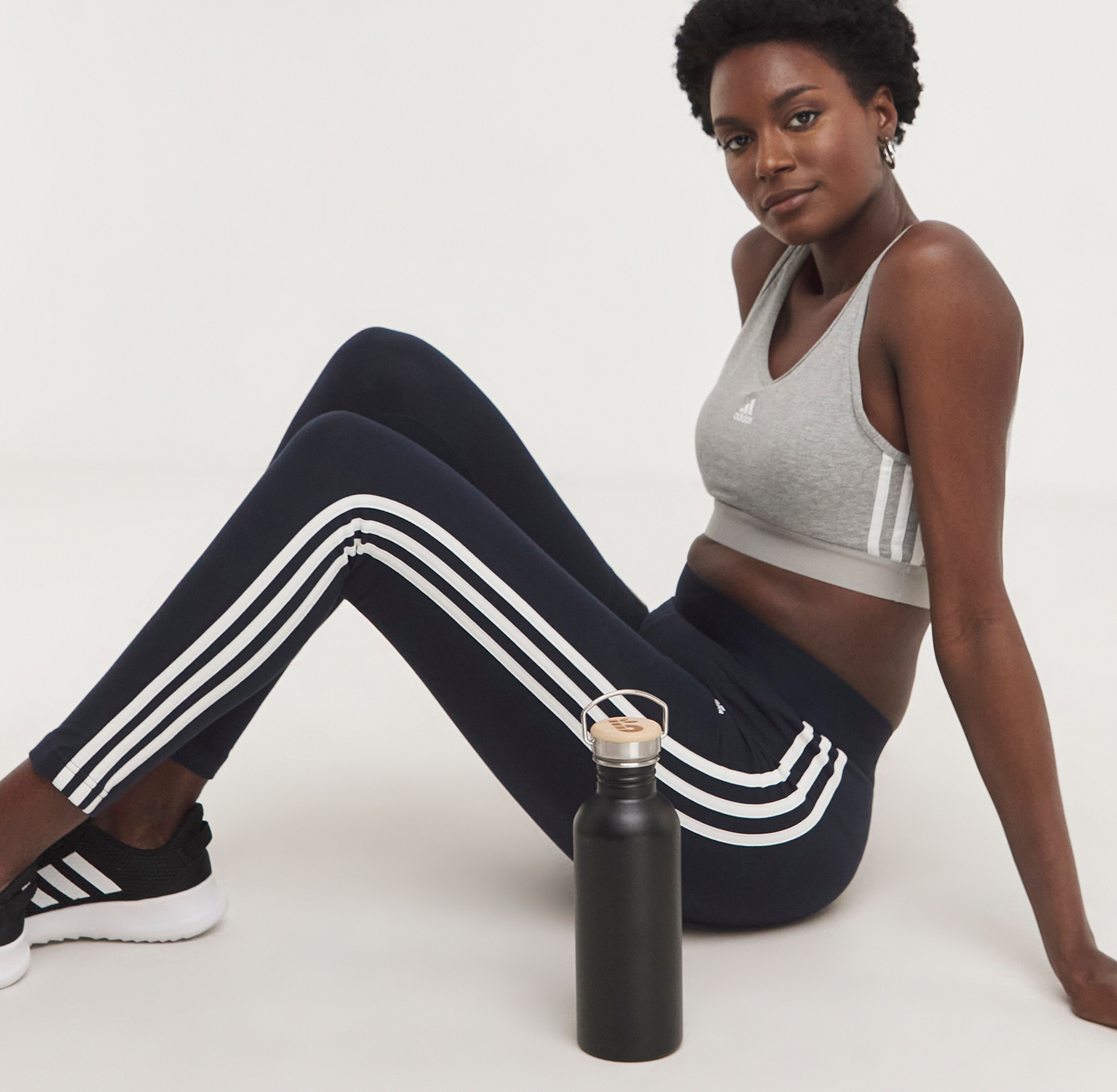 Woman wearing a grey vest and black tracksuit pants with black trainers