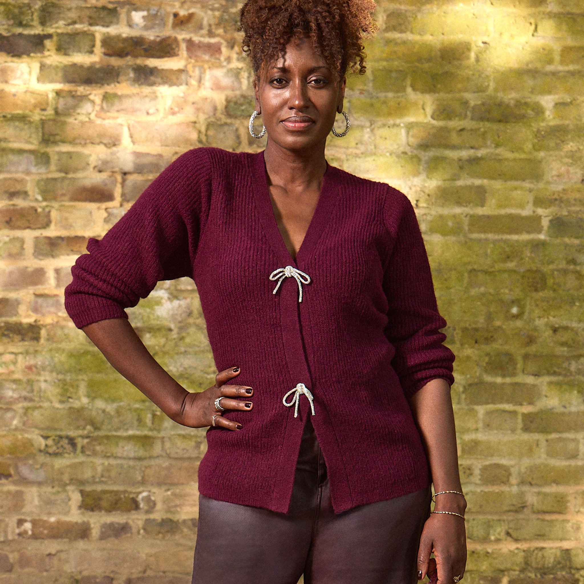 A lady stood wearing a maroon cardigan with two toggle fastenings