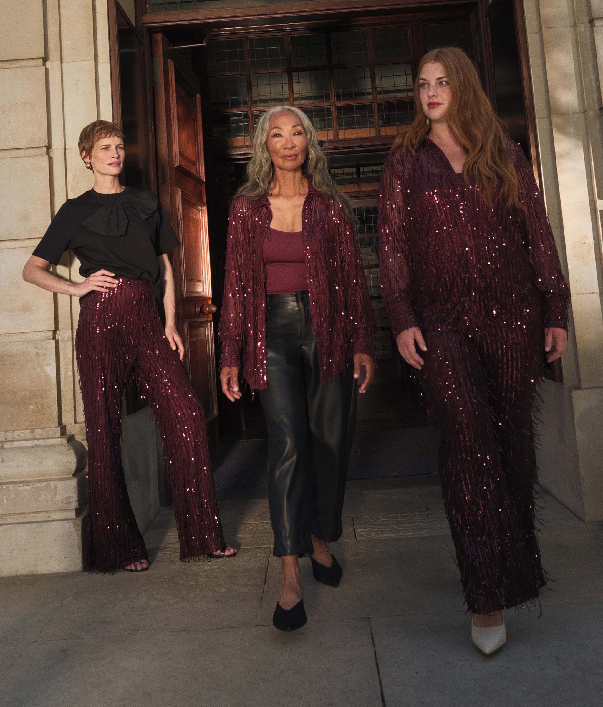 3 ladies walking out of a building wearing party outfits.