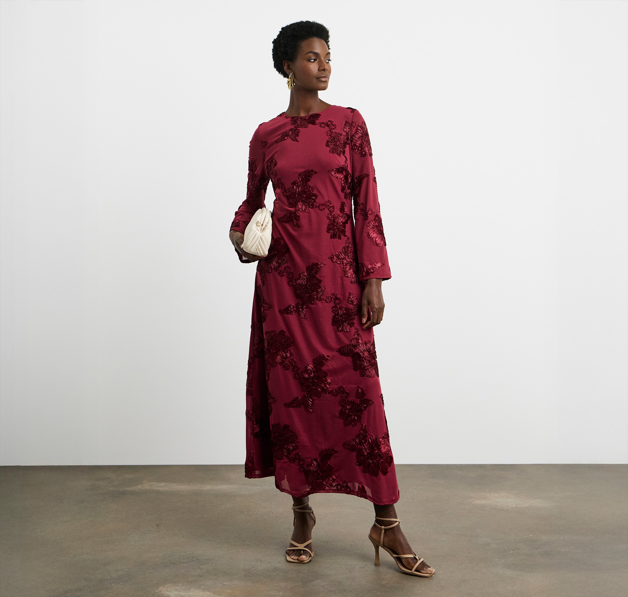 A lady wearing a ruby coloured dress with embroidered flowers