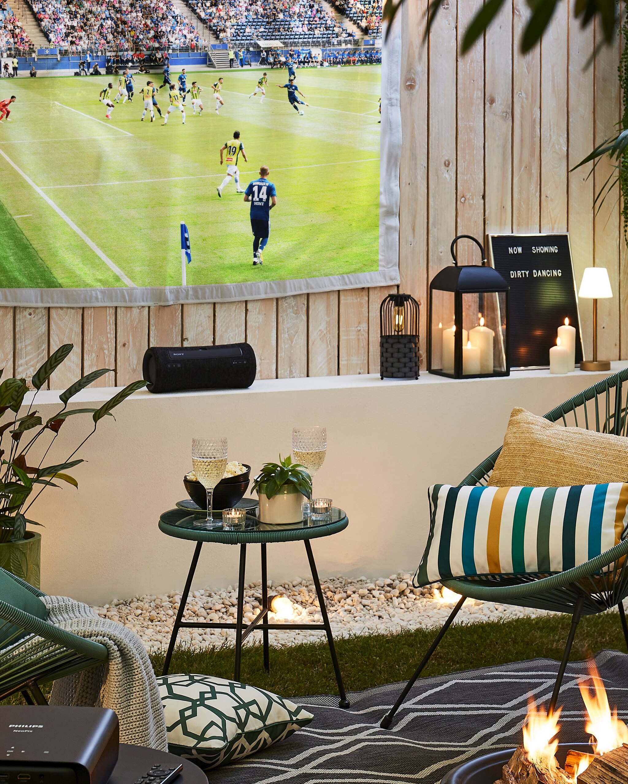A football match being projected onto a screen in the garden or outdoors