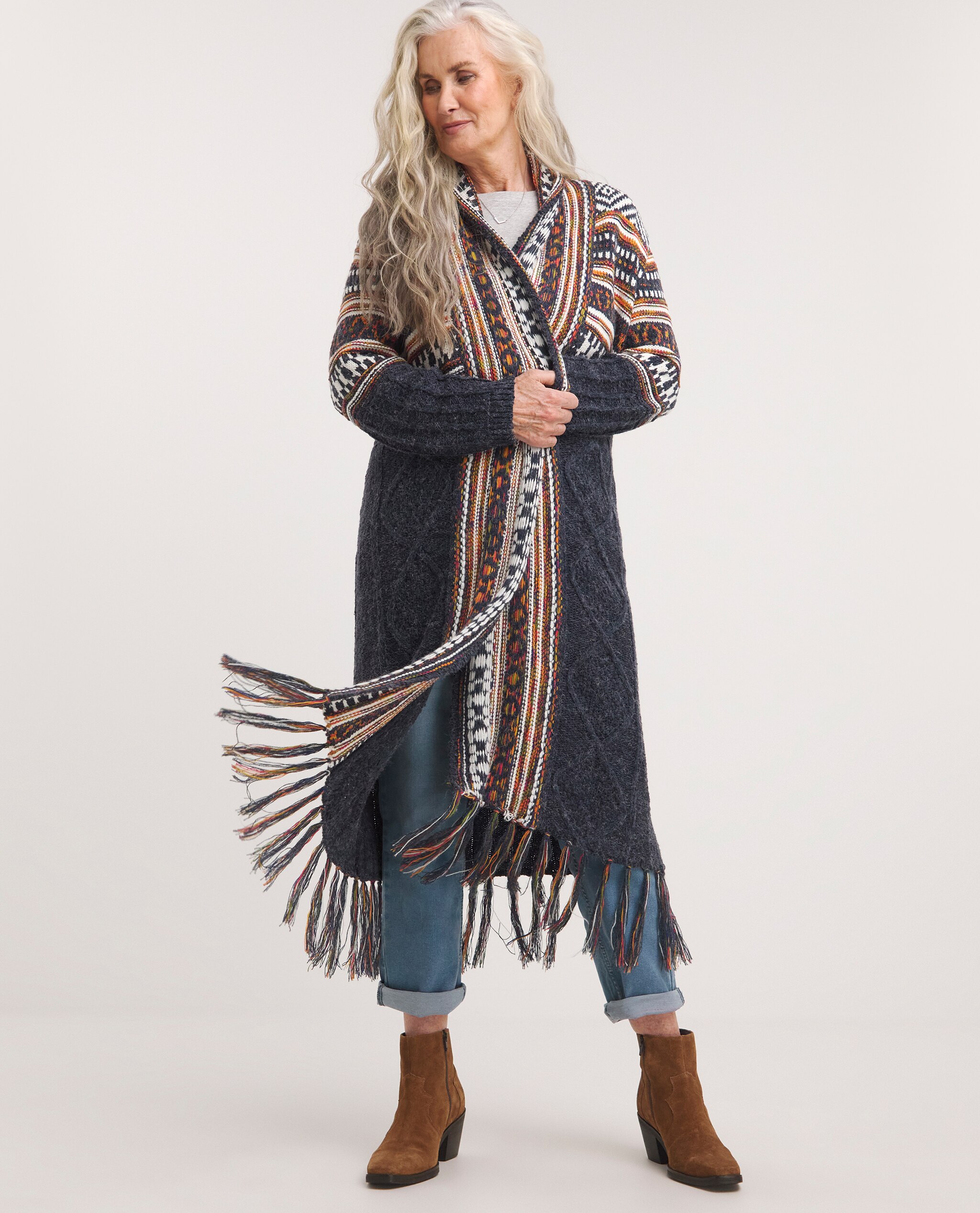 Model is wearing longline tassel hem cardigan with blue denim jeans and tan ankle boots.