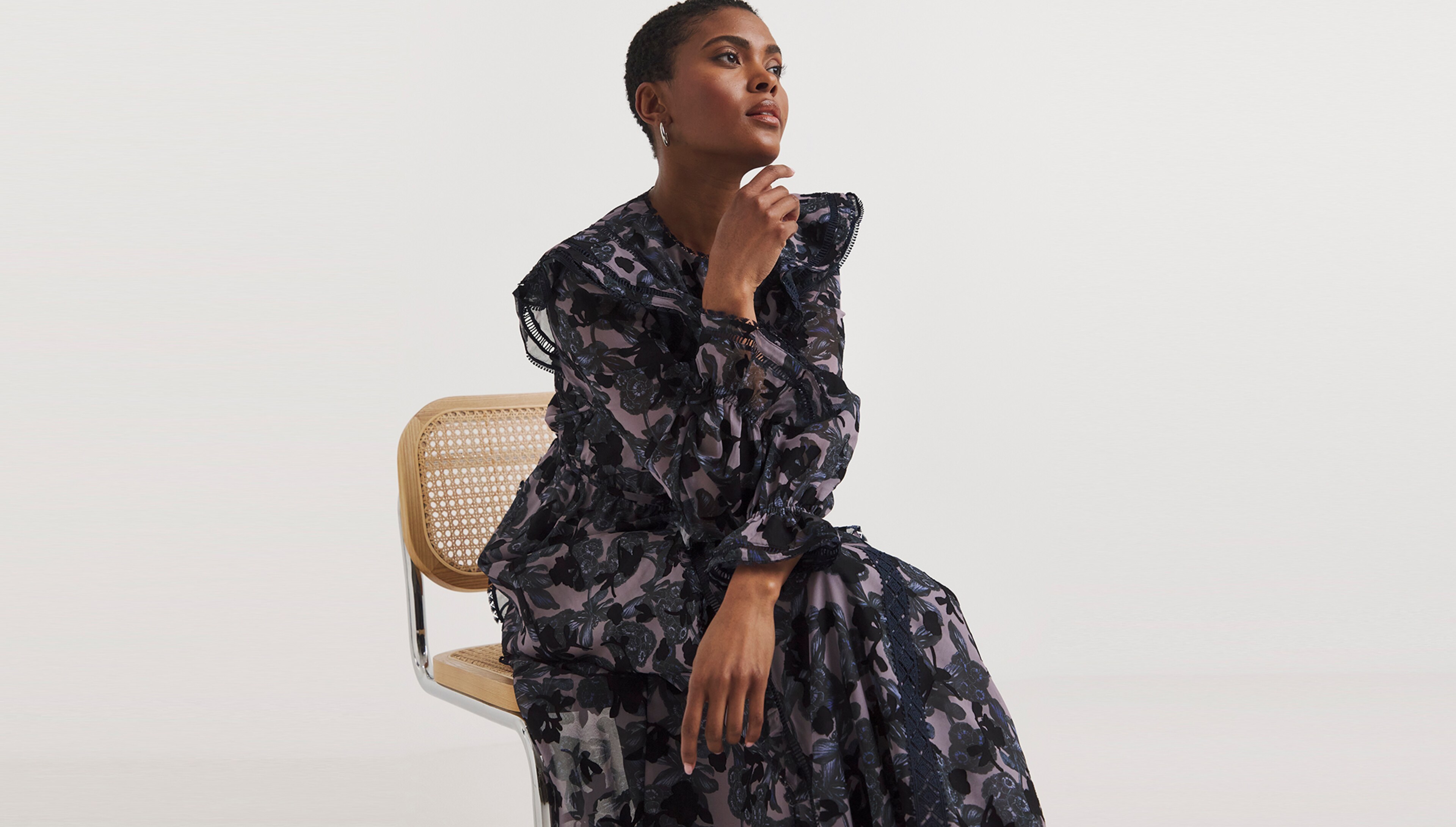 Woman sat wearing a black and patterned dress