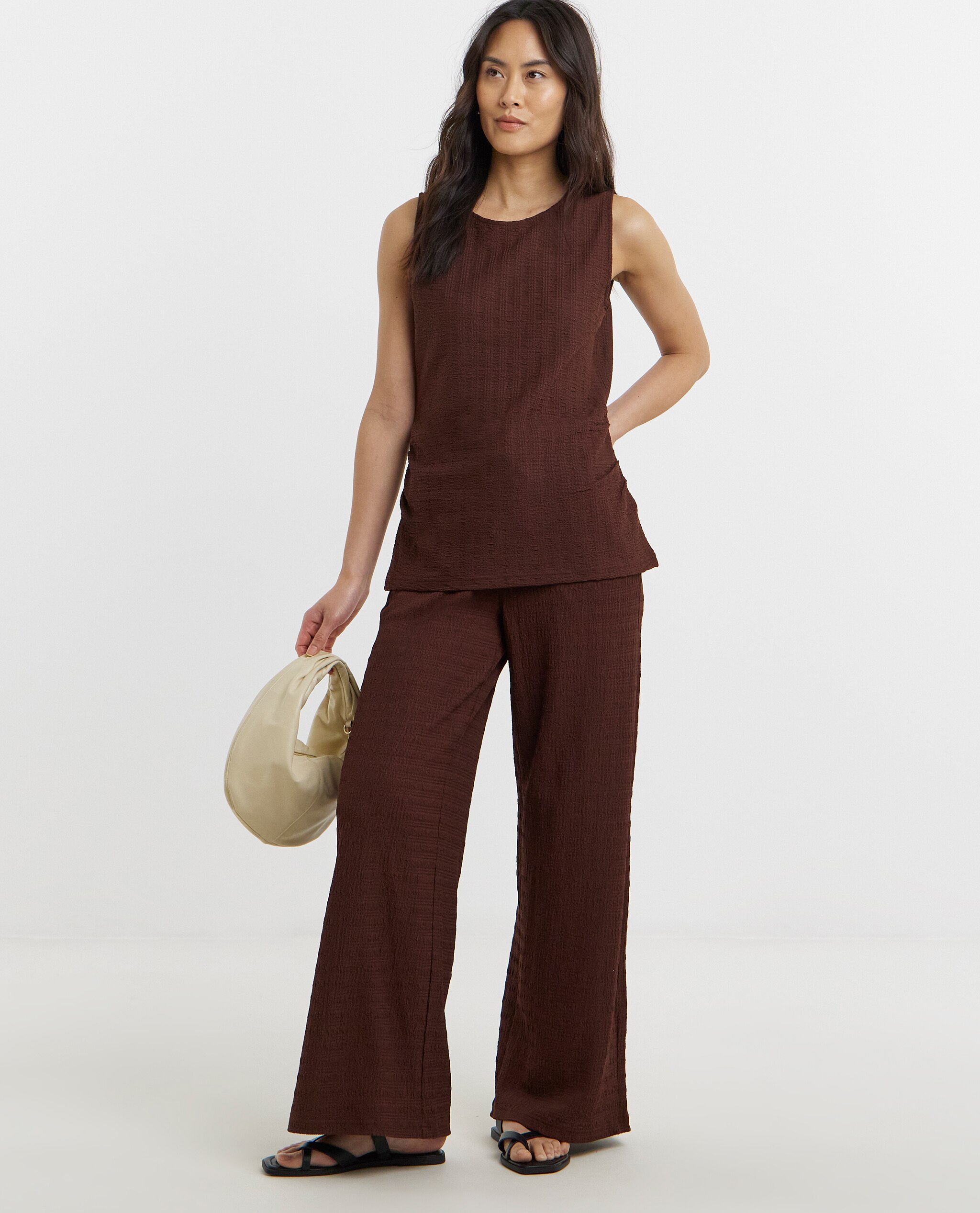 Model is wearing a chocolate textured ruched side top with chocolate jersey wide leg trousers.