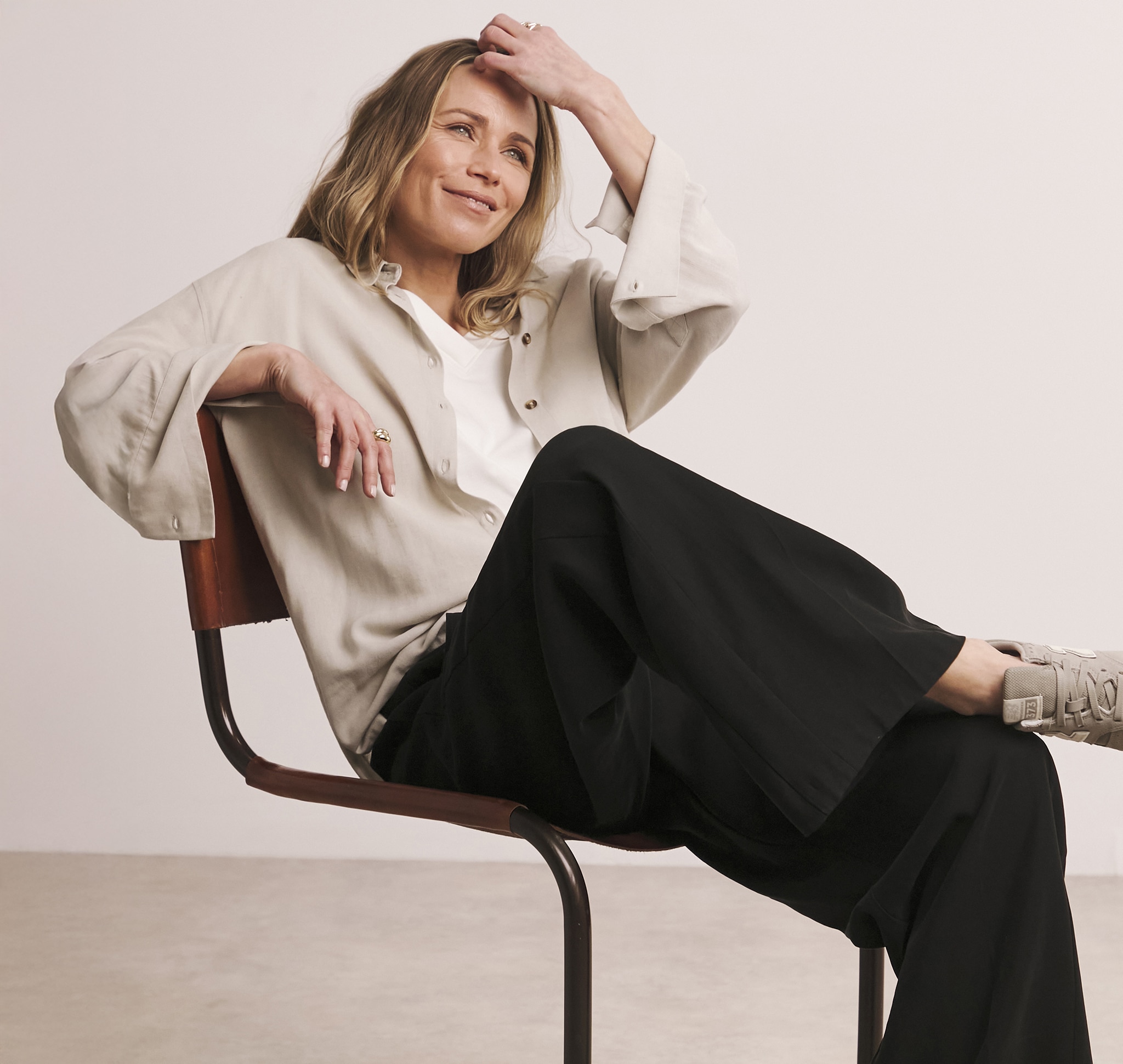 A lady sat on a chair wearing black wide leg trousers.