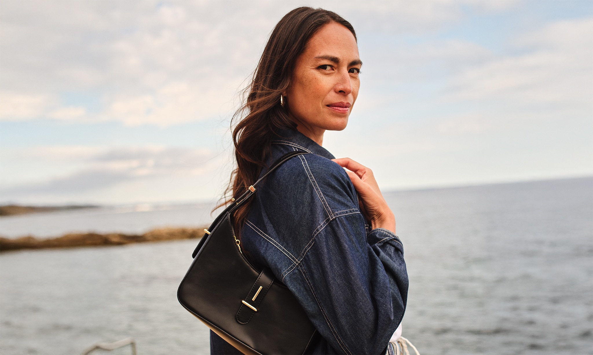 Lady wearing a denim jacket looking over her right shoulder.