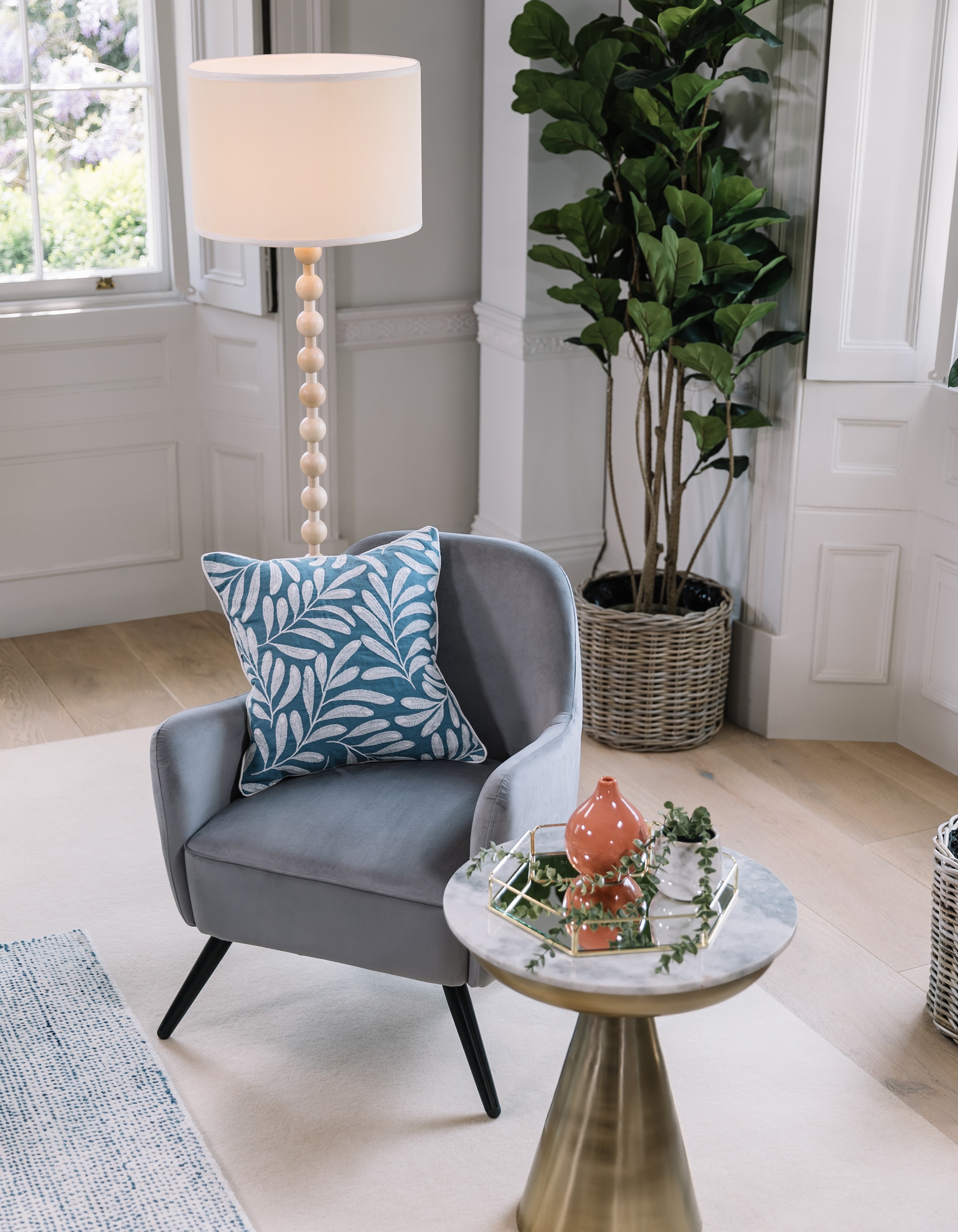 A grey chair with standard lamp next to it