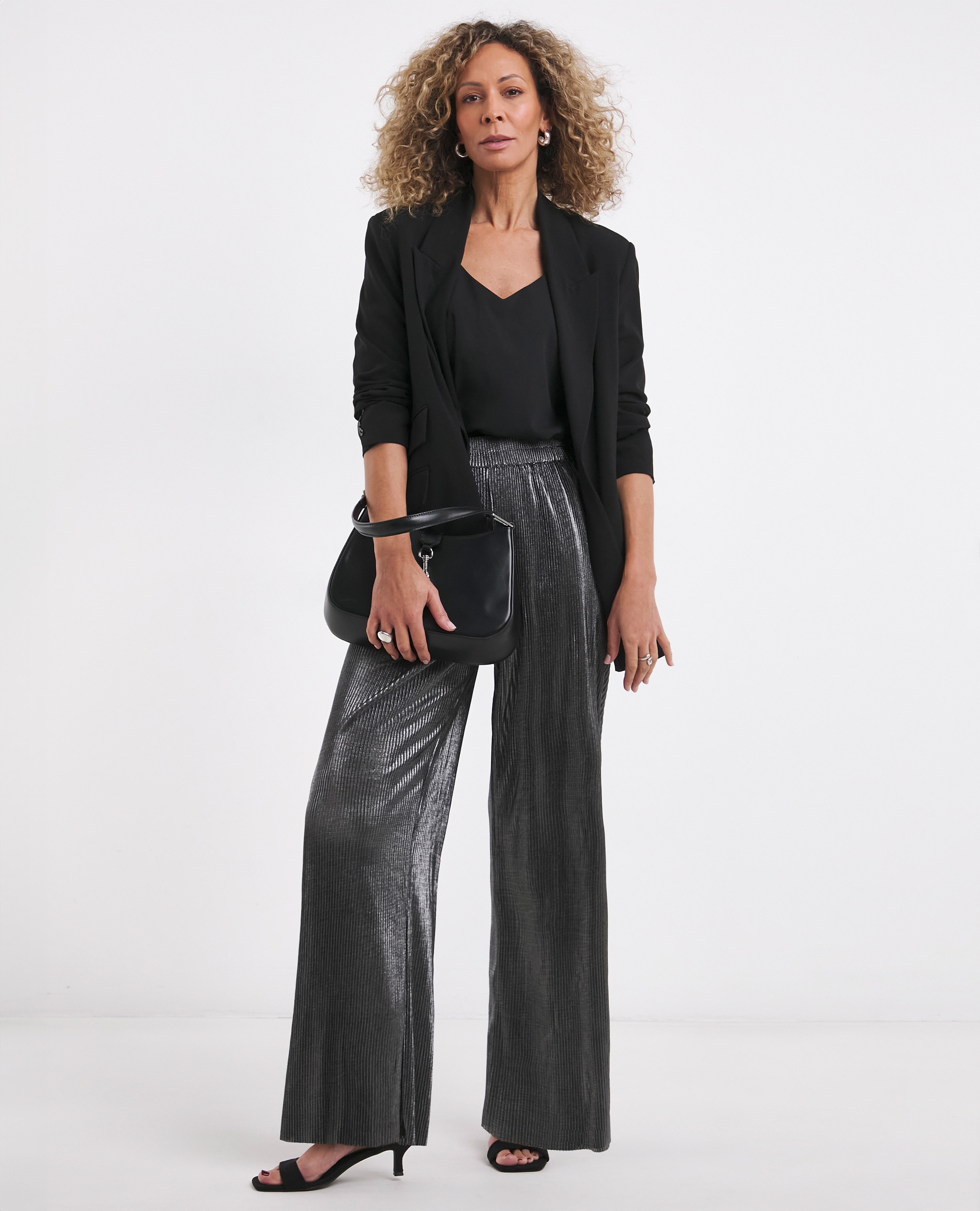 Model wearing silver high waisted trousers with a black blazer