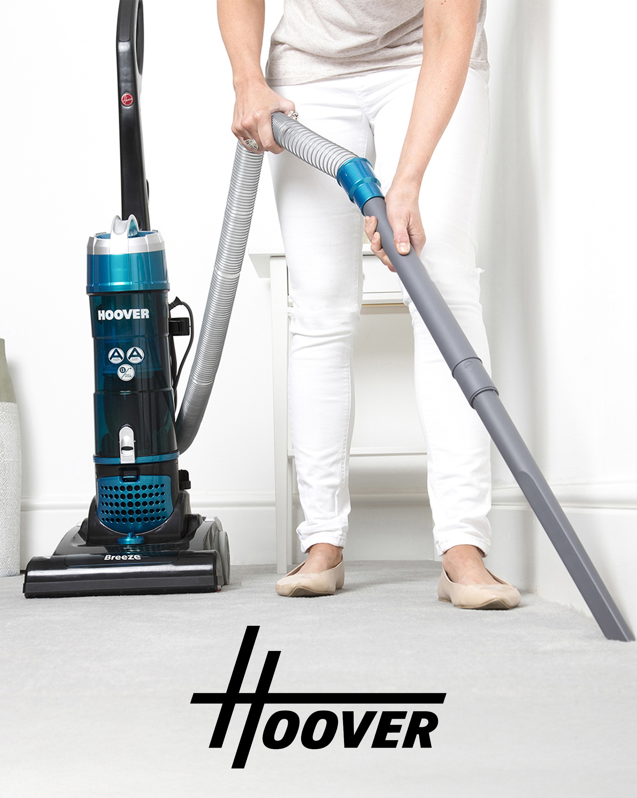 A person using a Hoover corded vacuum cleaner.